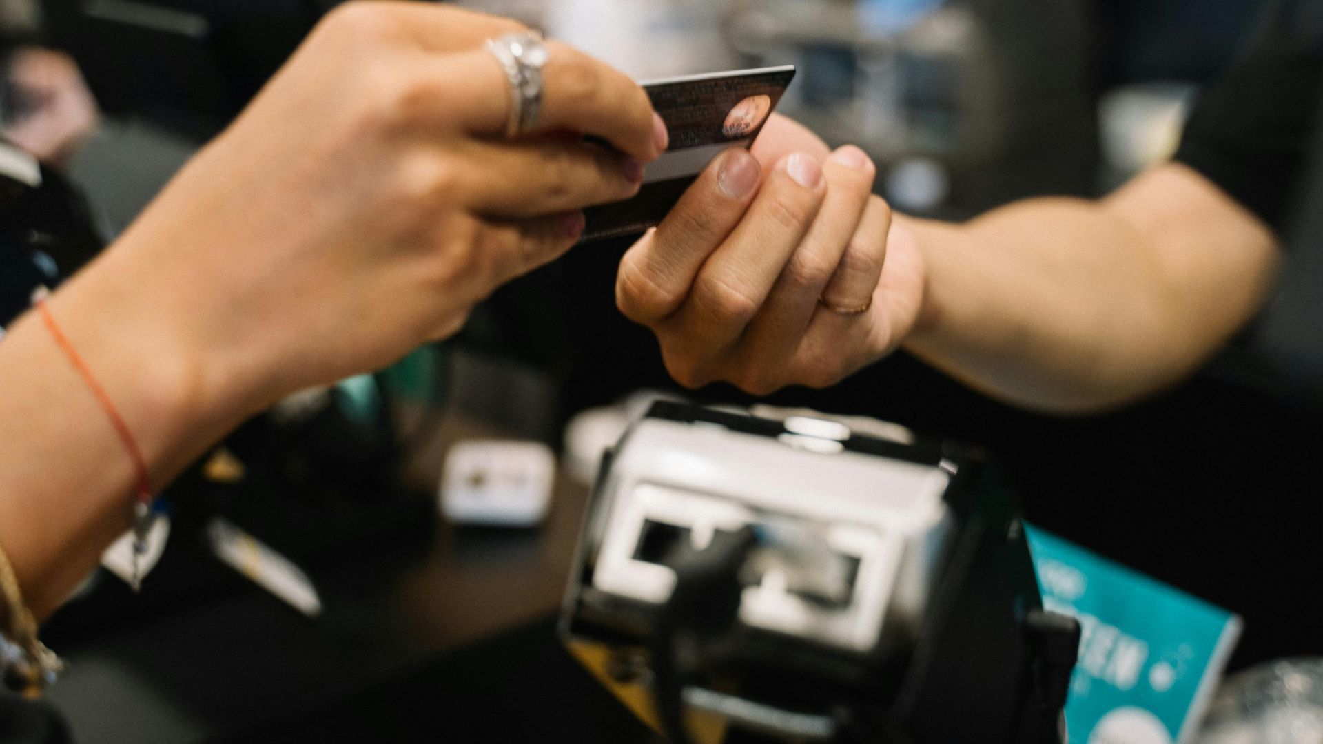 Close-up of hands completing a payment transaction at a retail checkout using a bank card.