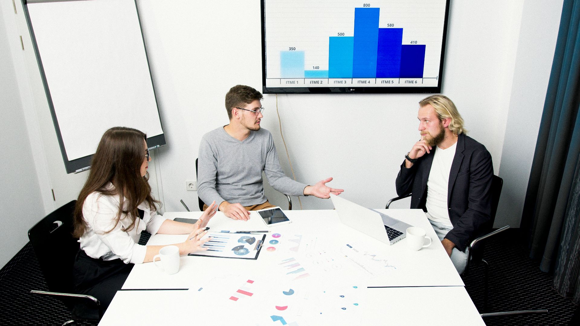 Professional team discusses strategies in a modern office environment with digital charts.