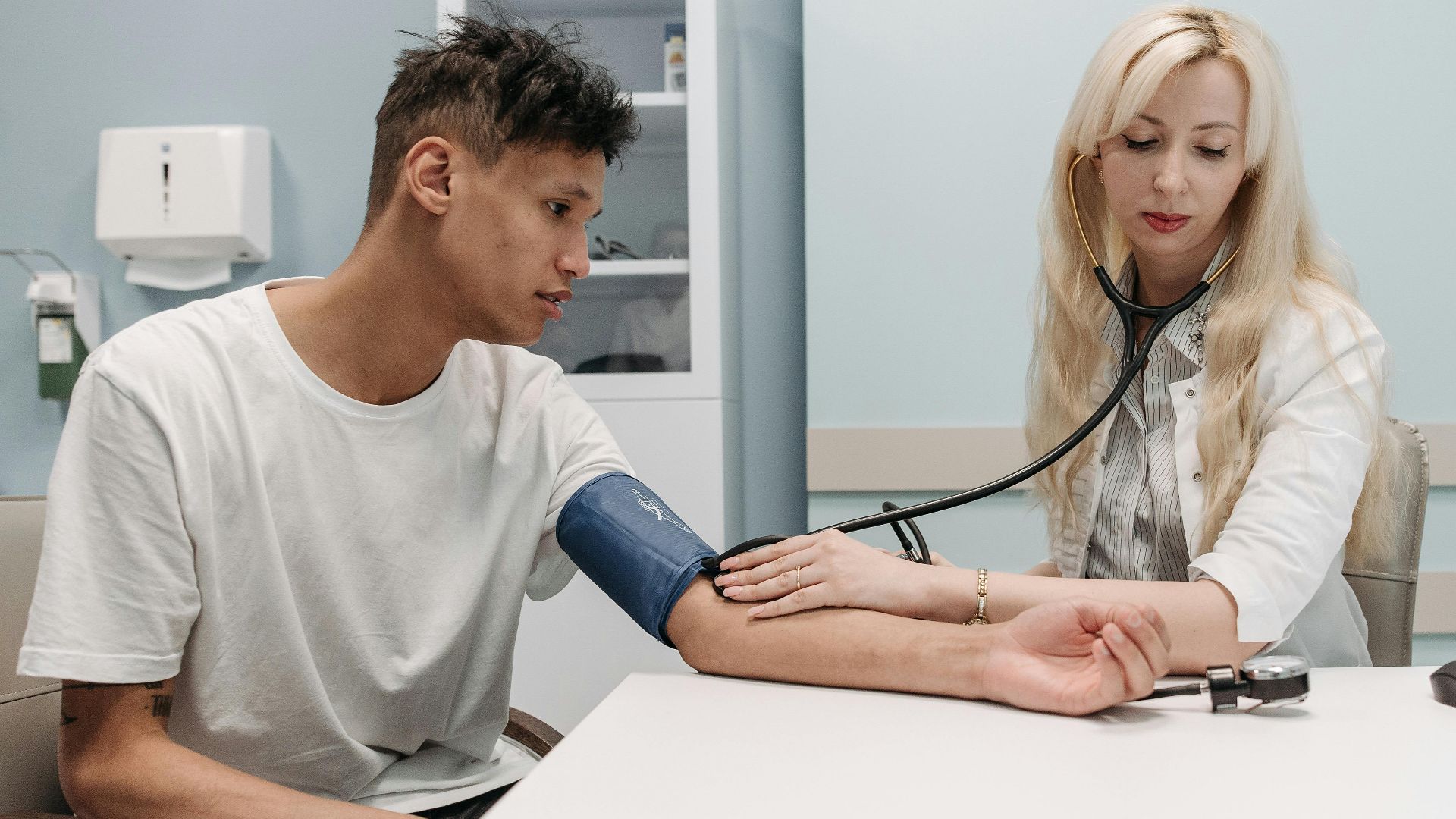 A doctor measures a patient's blood pressure in a clinic setting, focusing on healthcare and wellness.