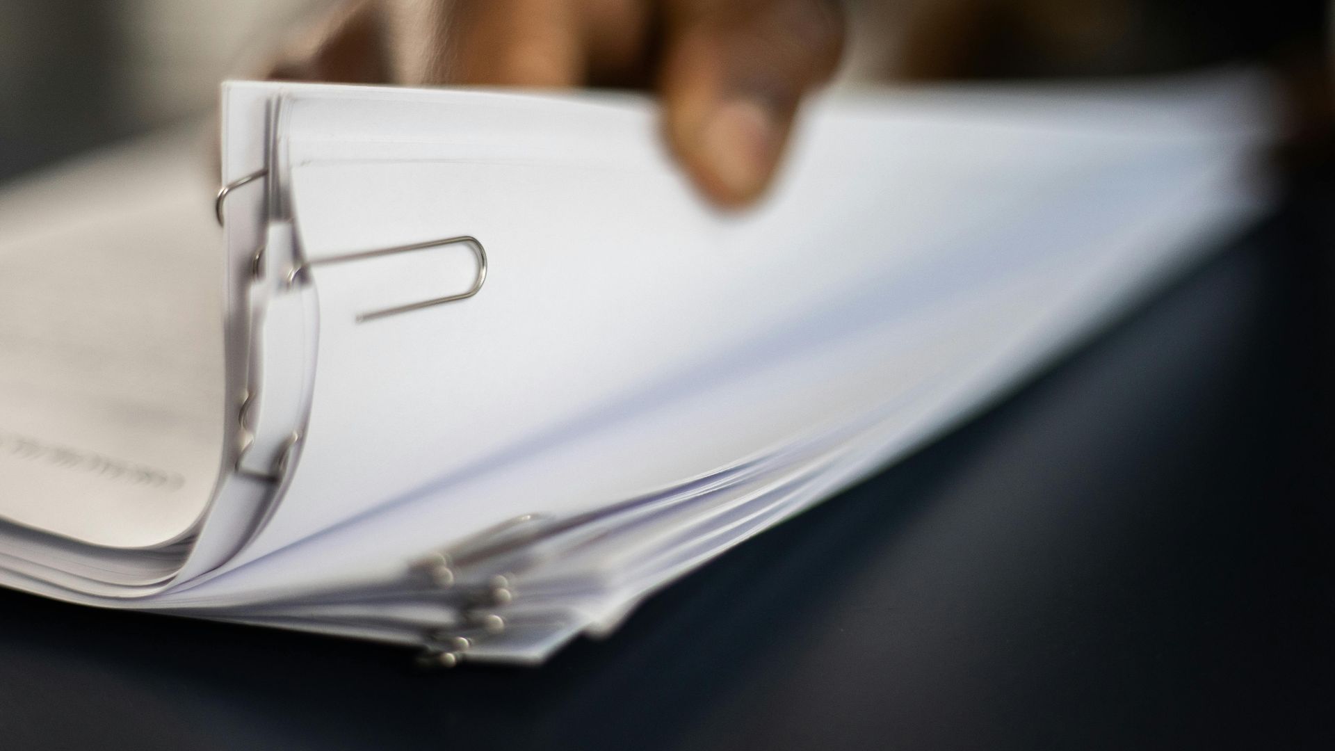 Detailed image of paper stacks held together by paperclips, showcasing organizational tools.