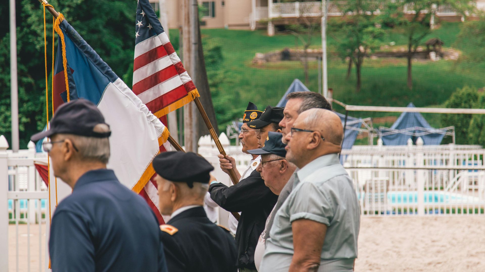 Group of veterans holding flags during an outdoor ceremony showing patriotism.