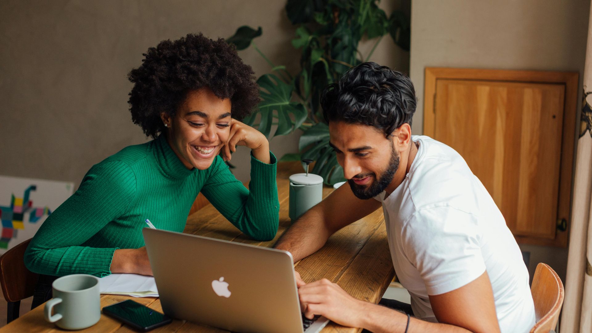 Two colleagues engaged in teamwork, brainstorming ideas on a laptop in a cozy office setting.