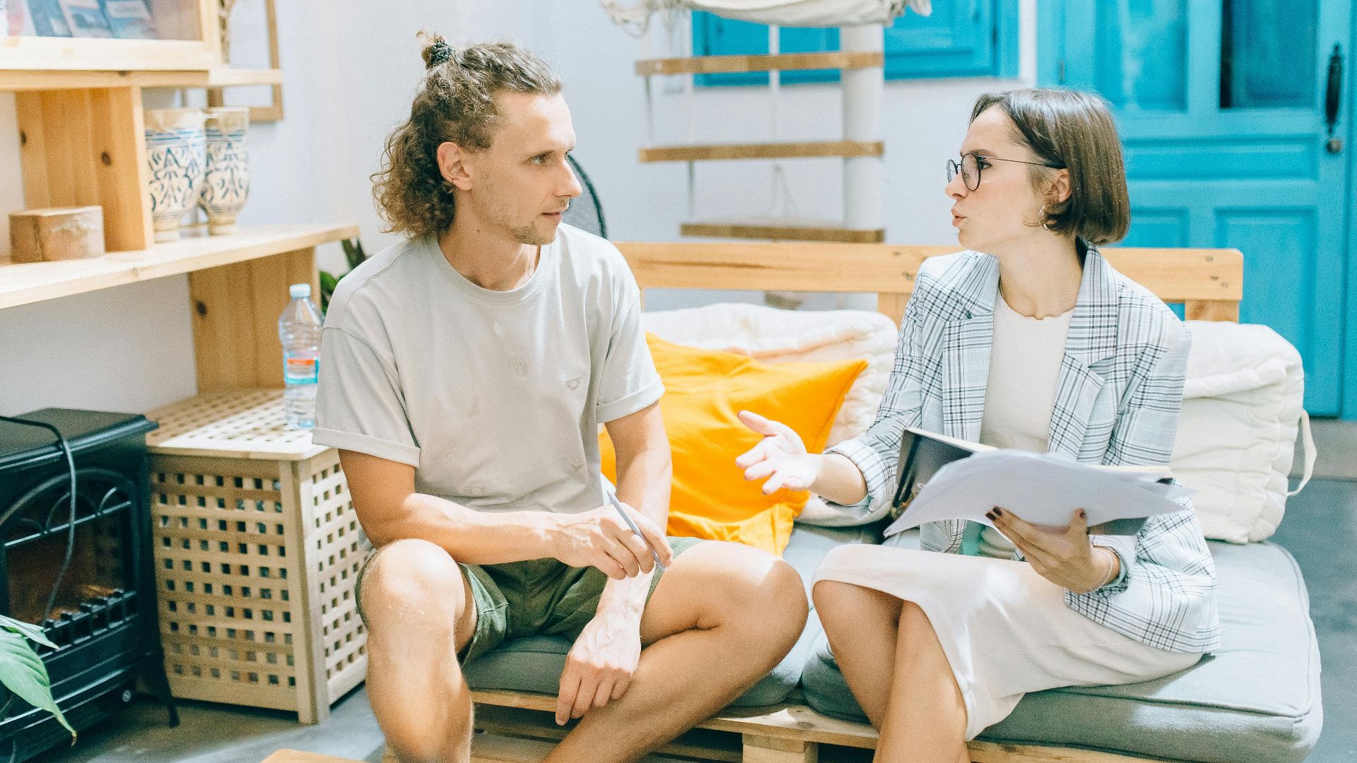 A man and woman discussing work in a stylish, bright living room setting.
