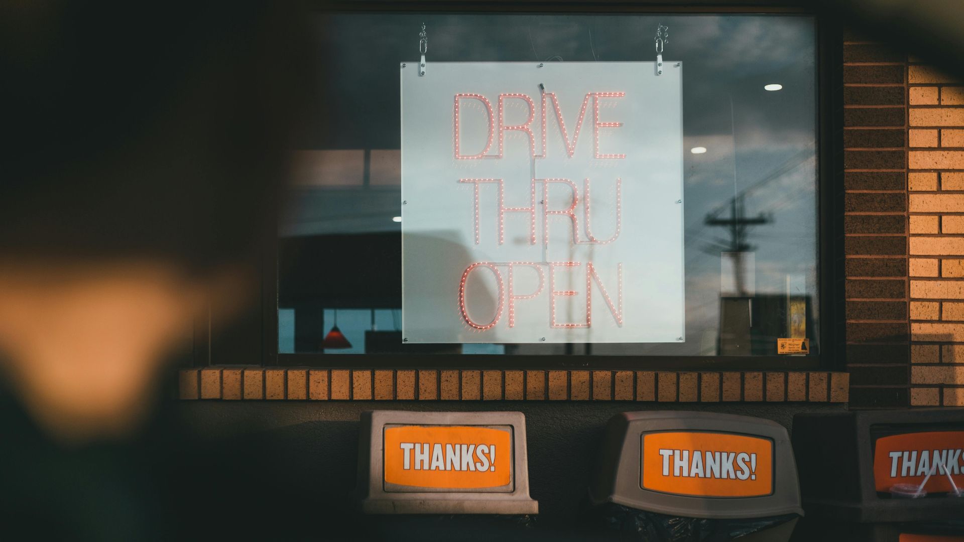 Drive thru service window with open sign at a fast food location. Daytime setting.