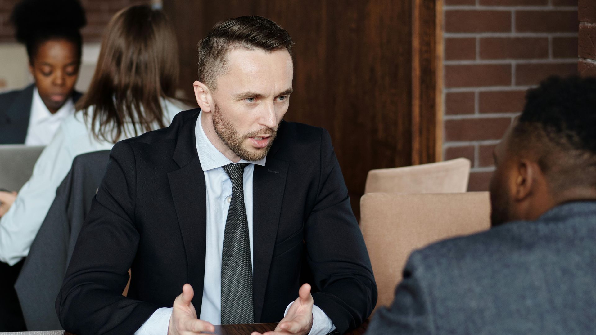 Professionals in suits having a focused business discussion in a stylish café.
