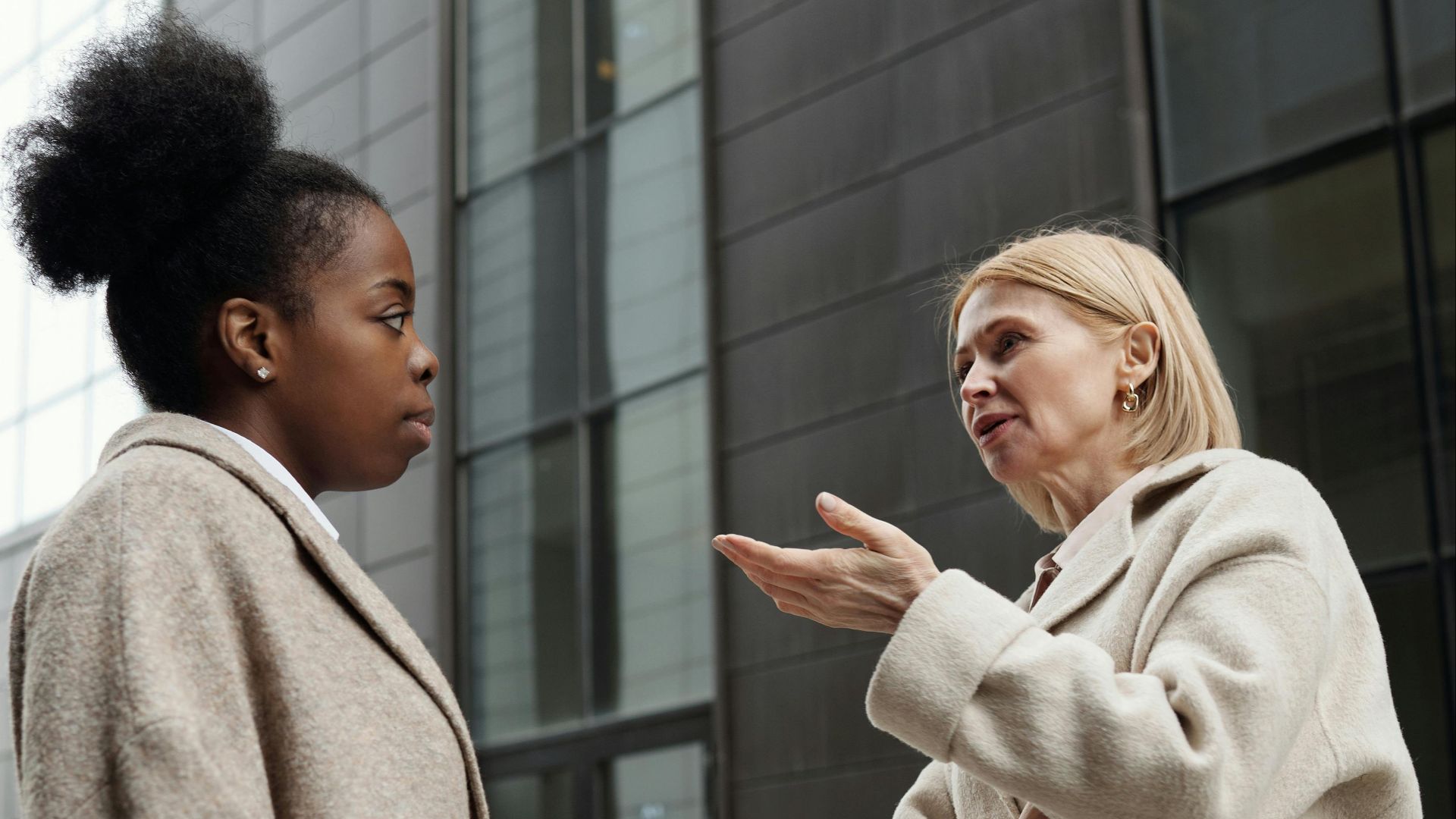 Two businesswomen having a conversation outside a modern building in an urban area.