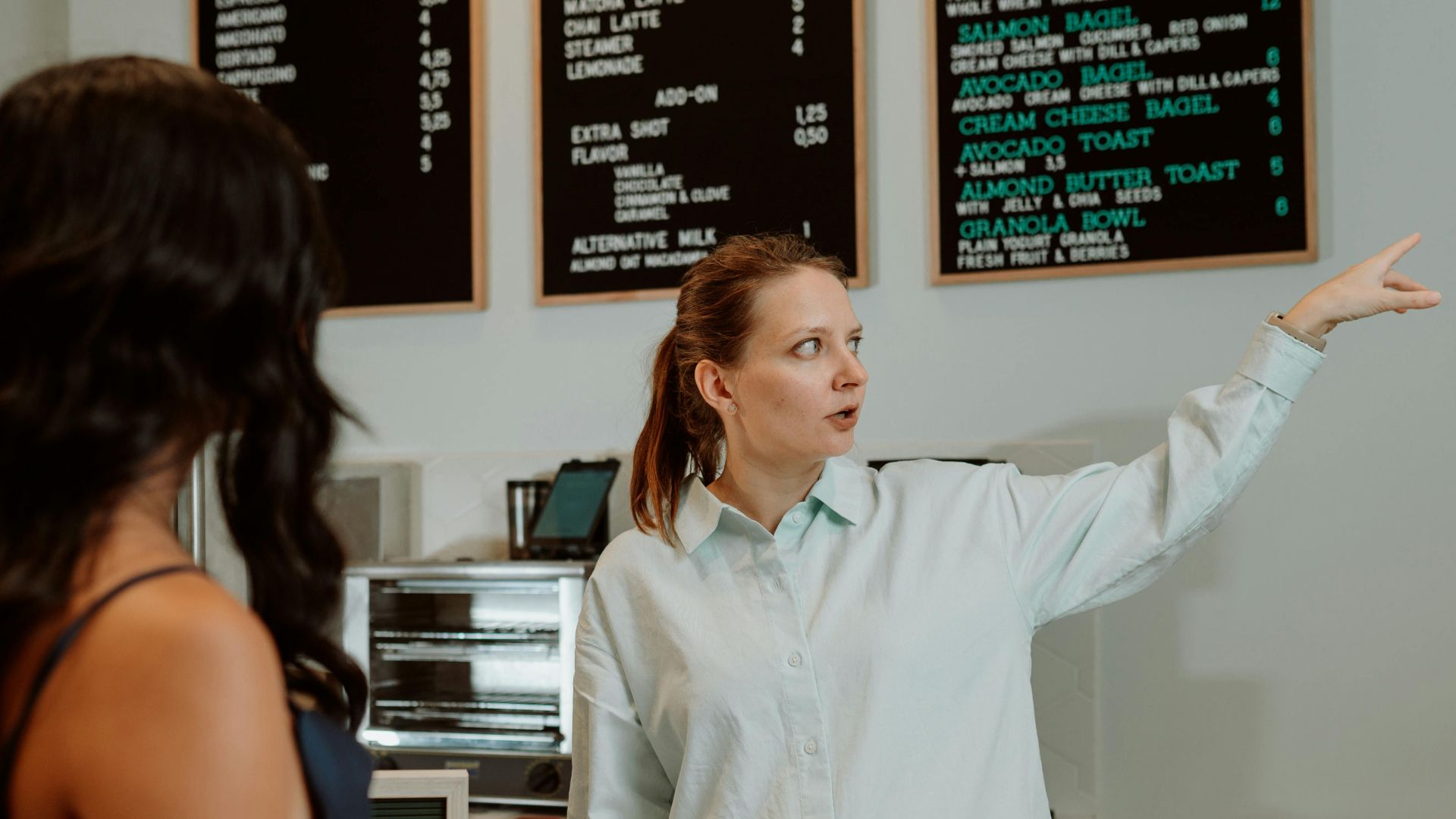 A barista attentively assists a customer at a modern café, showcasing a professional service setting.