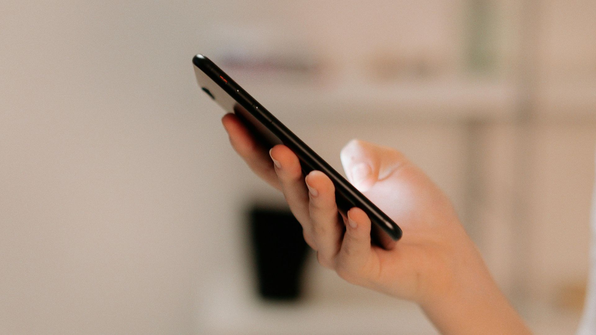 Close-up of a person using a smartphone indoors, focusing on hand and device.