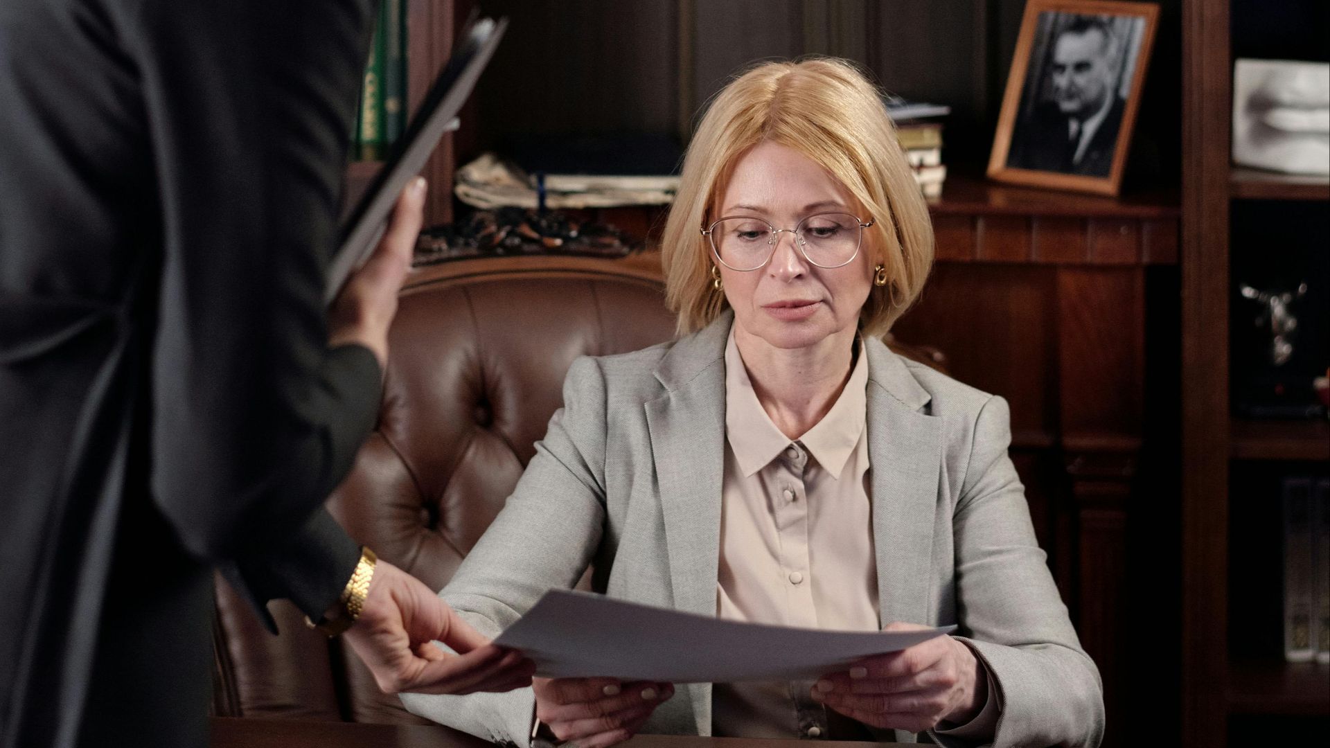 Two businesswomen reviewing documents in a classic office setting.