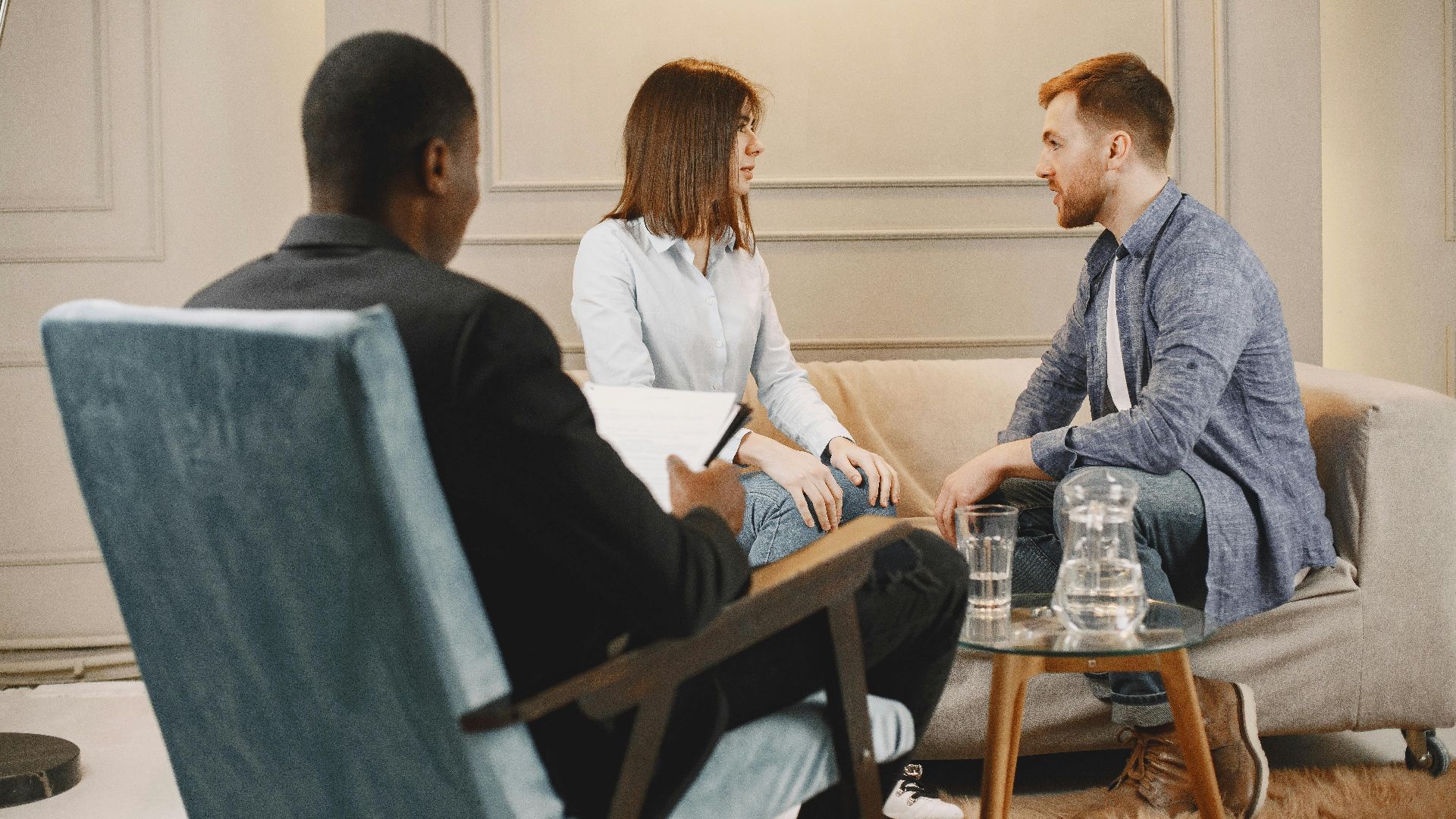 Couple in a counseling session with a therapist in a modern and cozy setting.