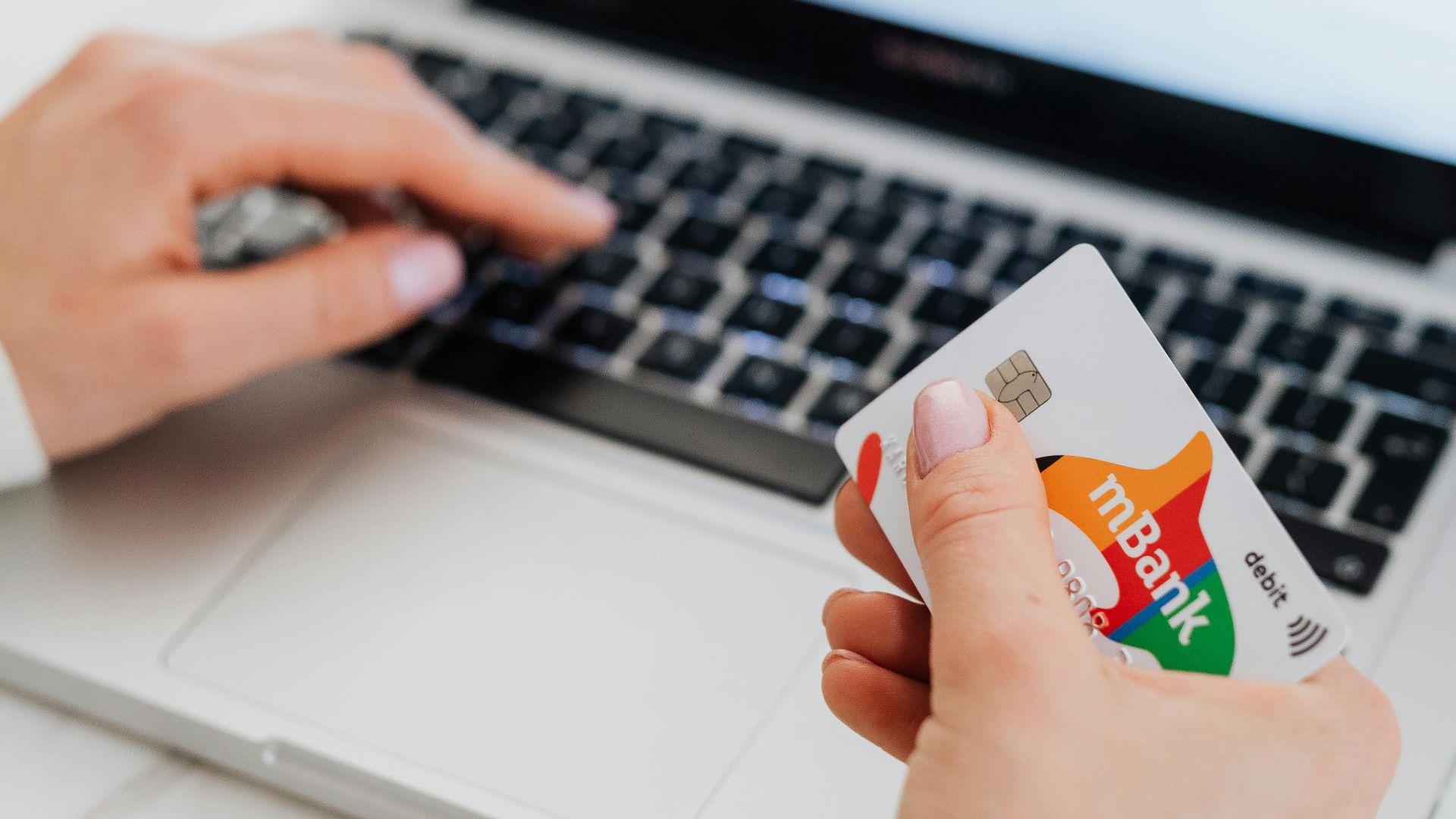 Person using a credit card for online shopping on a laptop, showcasing e-commerce concept.