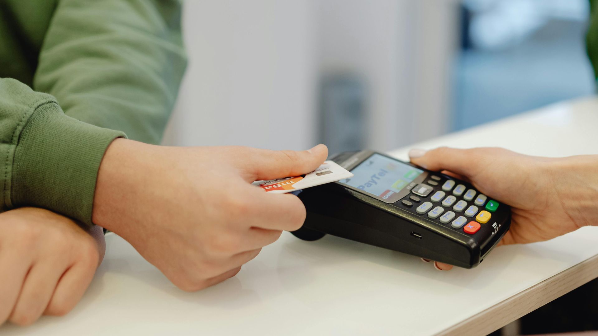 A close-up view of a contactless payment being made with a bank card over a payment terminal.