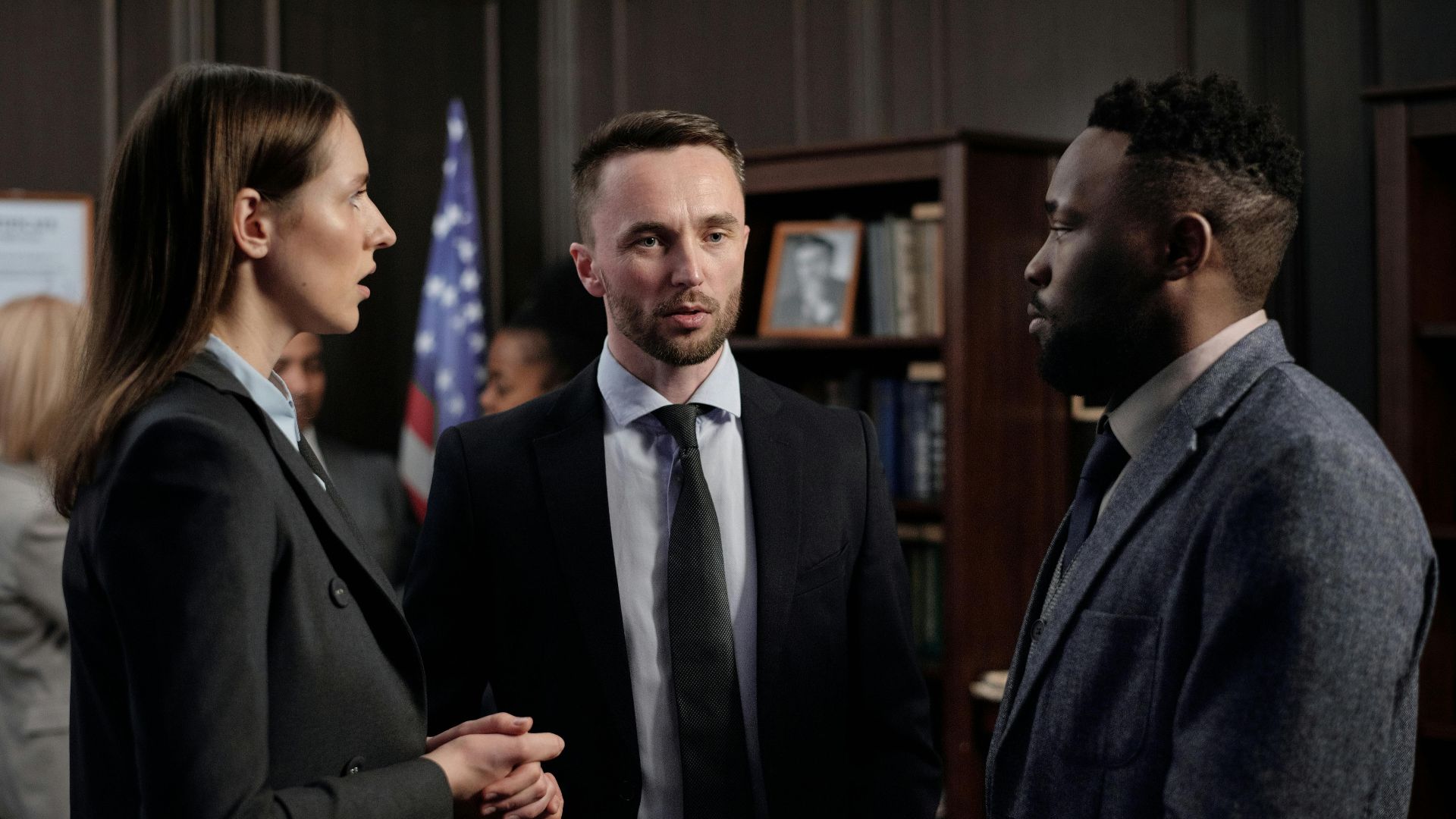 Group of business professionals engaged in a serious discussion inside an office environment.