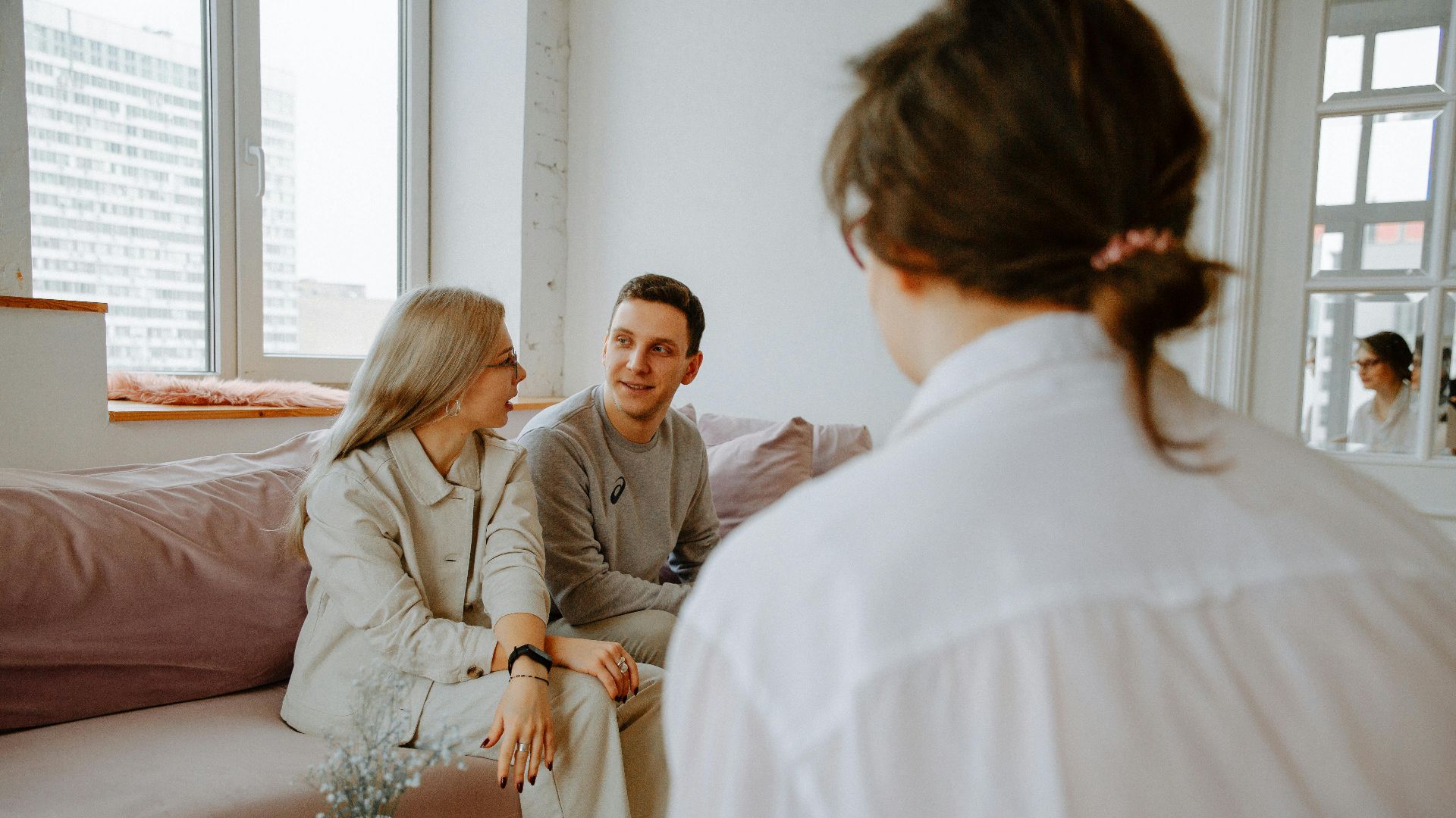 A couple engaged in a counseling session with a therapist in a modern indoor setting.