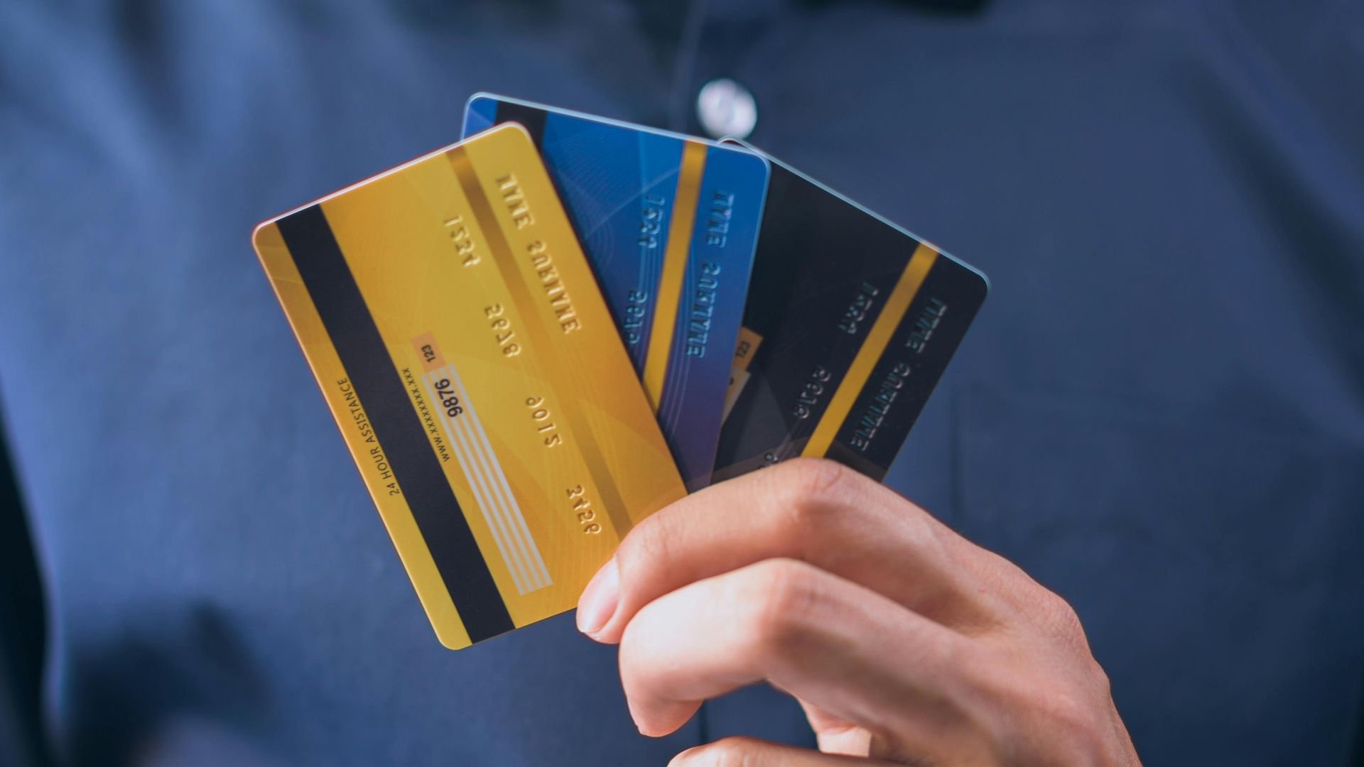 Person holding three credit cards, symbolizing finance, security, and e-commerce.