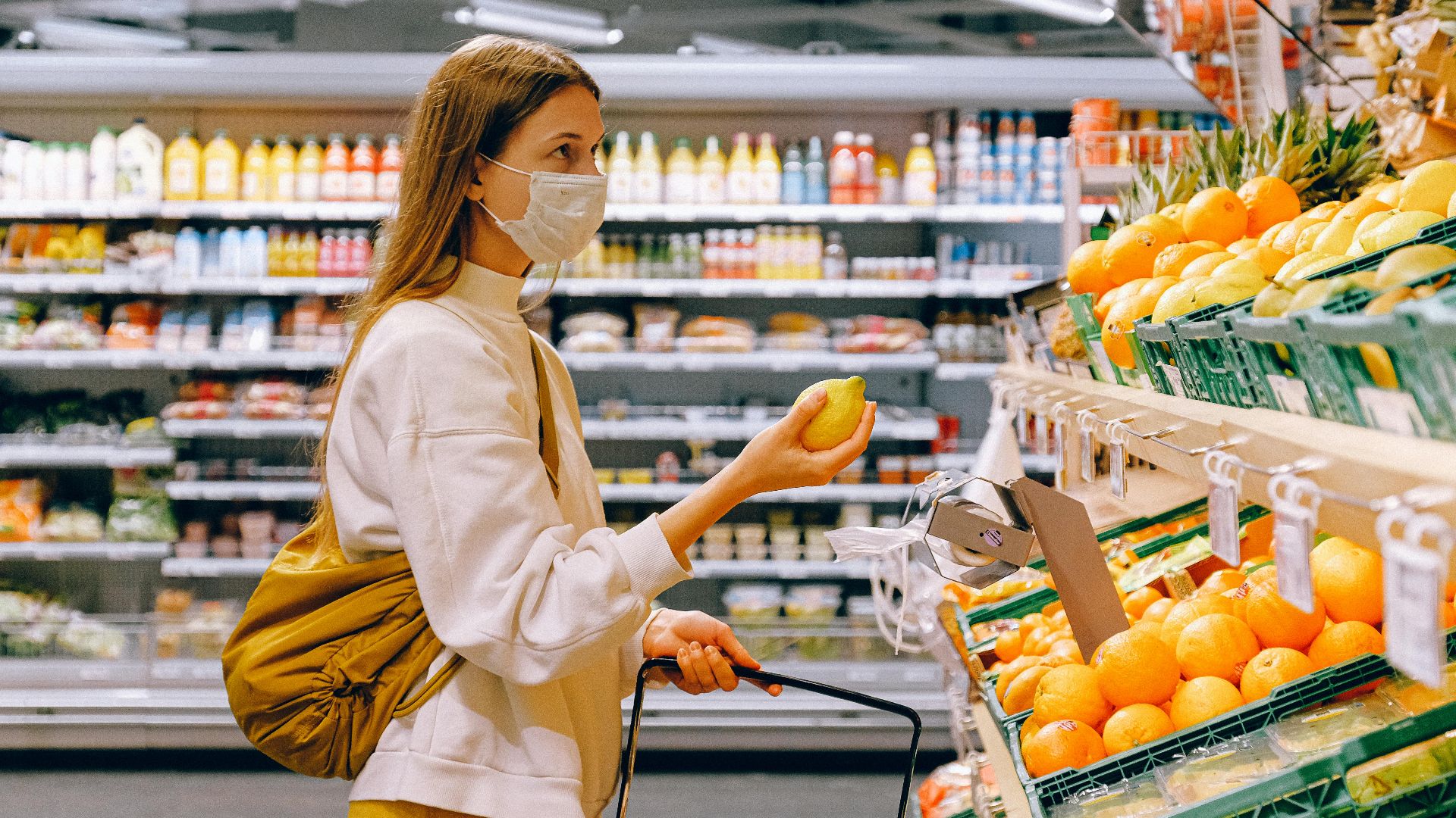 A woman wearing a face mask shops for fruits in a supermarket during a pandemic.