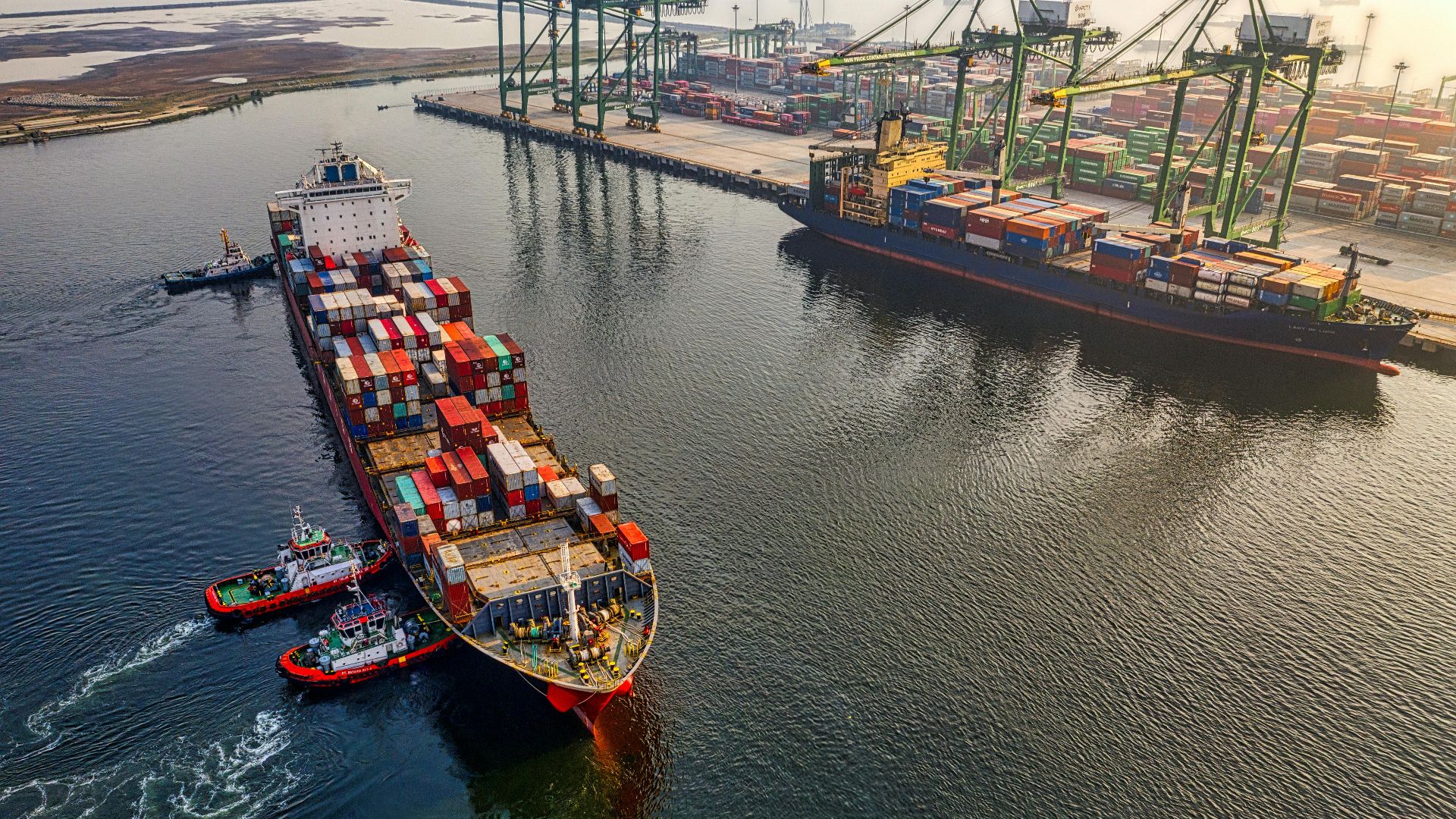 Aerial shot of cargo ships and cranes at North Jakarta port, showcasing global shipping and logistics.