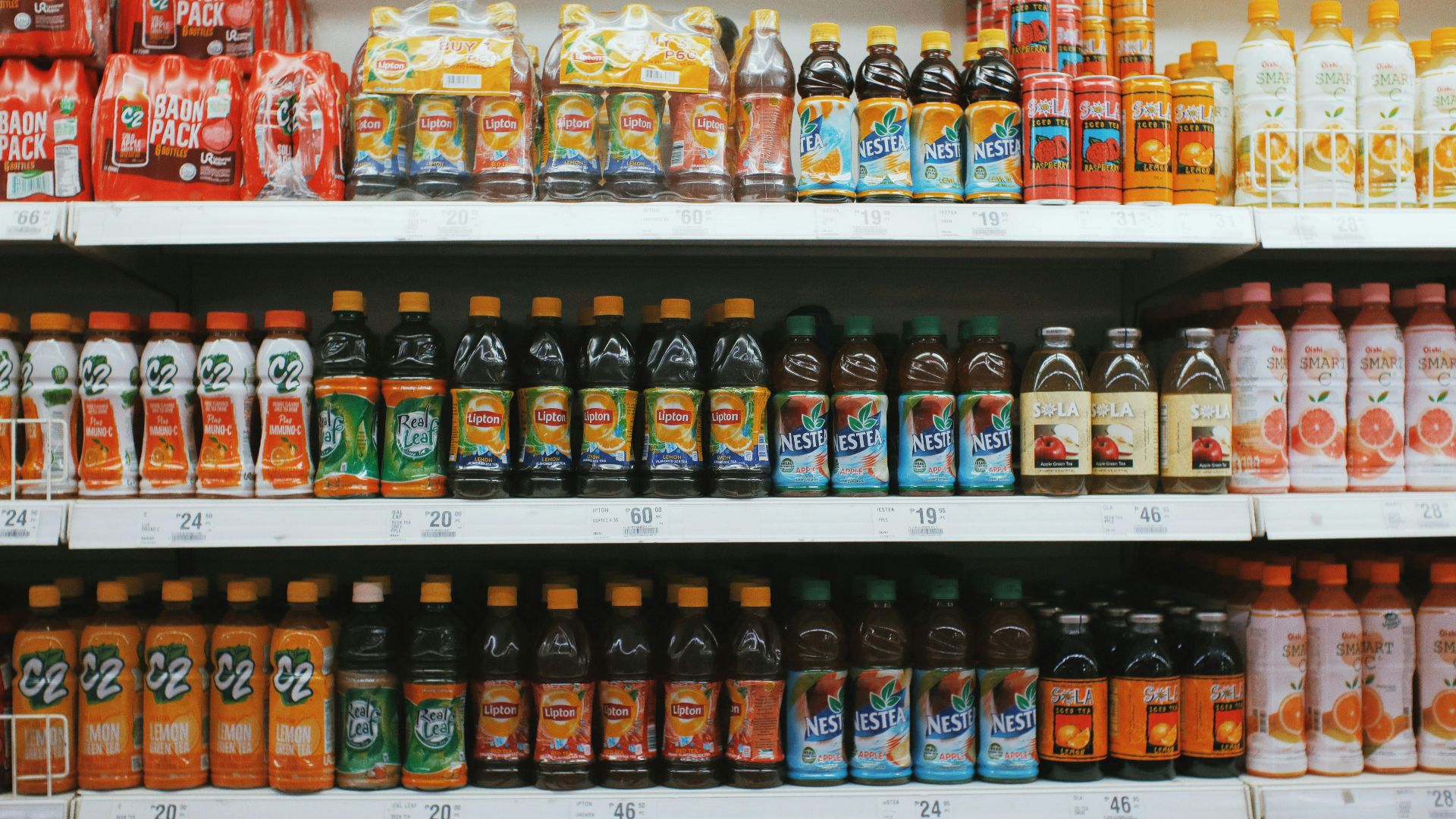 Vibrant rows of assorted drinks on a supermarket shelf, showcasing variety.