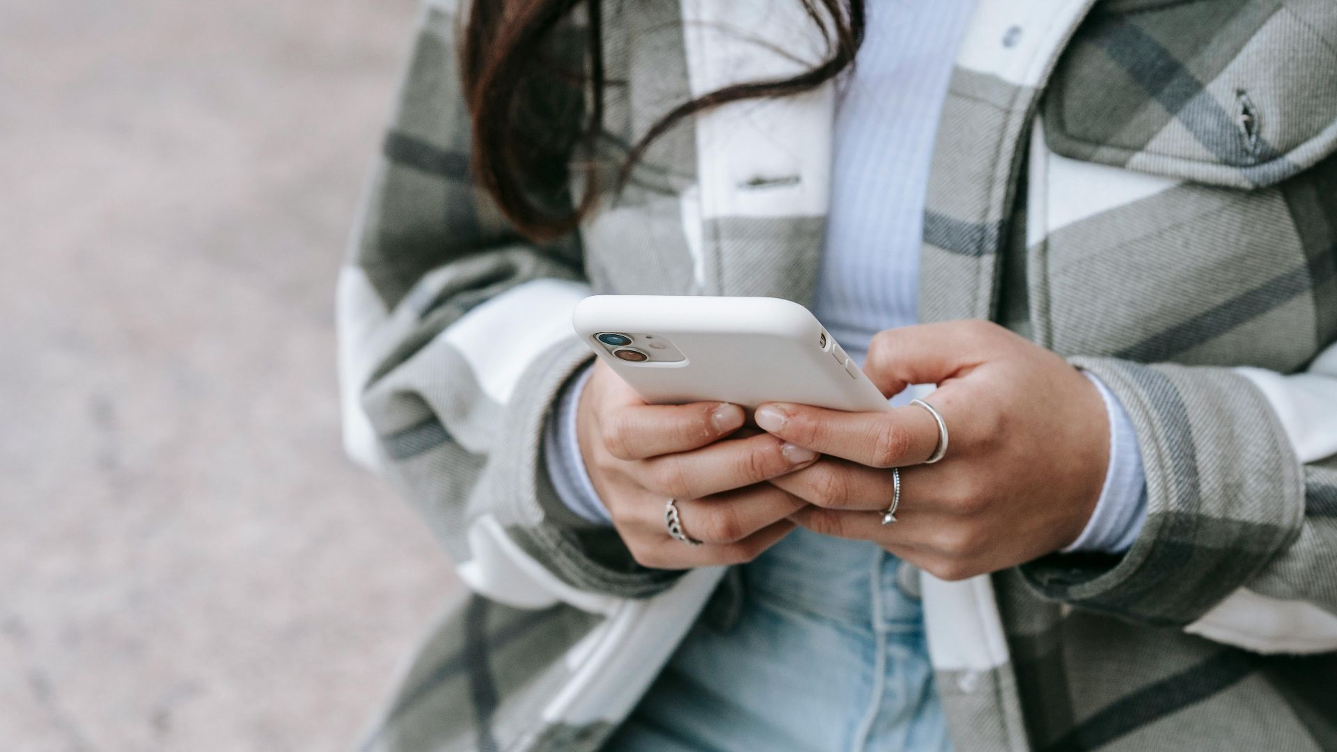 A woman using her smartphone while sitting outdoors, showcasing modern lifestyle and connectivity.