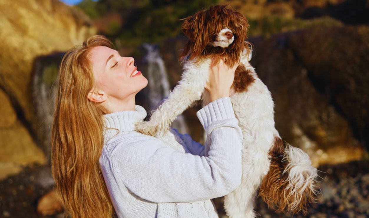 A Woman in Knitted Jacket Carrying a Dog
