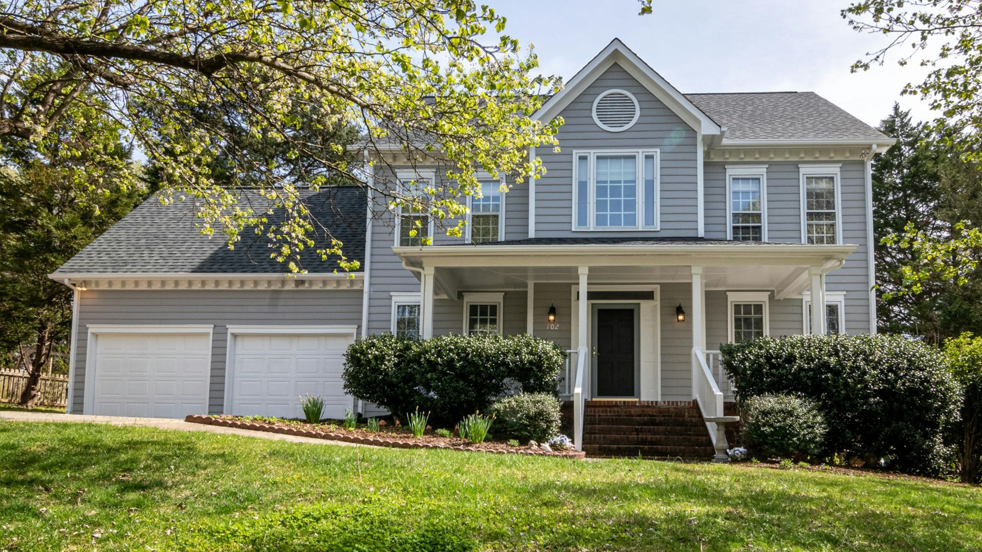 A beautiful suburban house surrounded by trees and lush greenery, perfect for families.