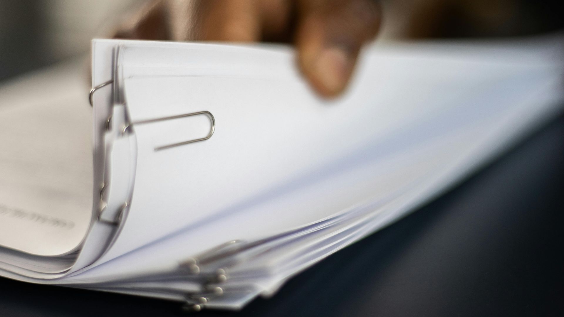 Detailed image of paper stacks held together by paperclips, showcasing organizational tools.