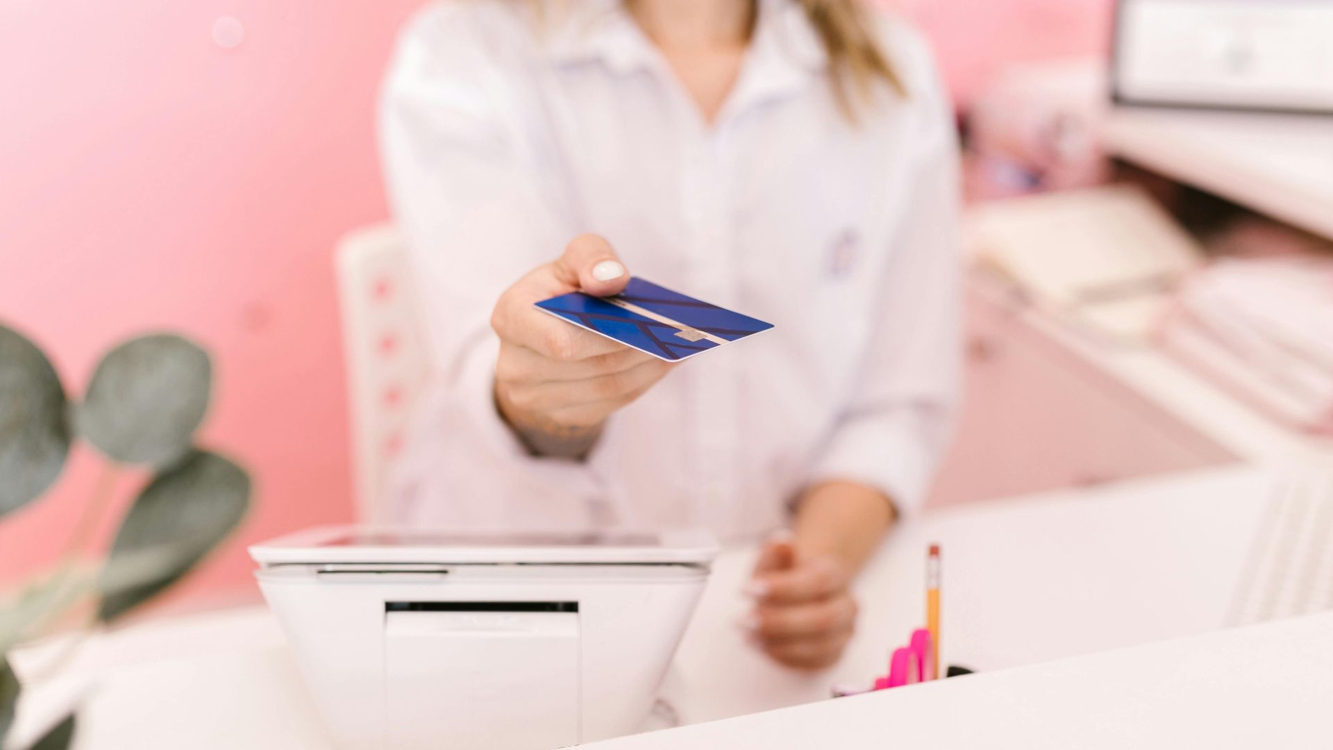 Blurred hands offering a credit card to a cashier at a modern retail counter.