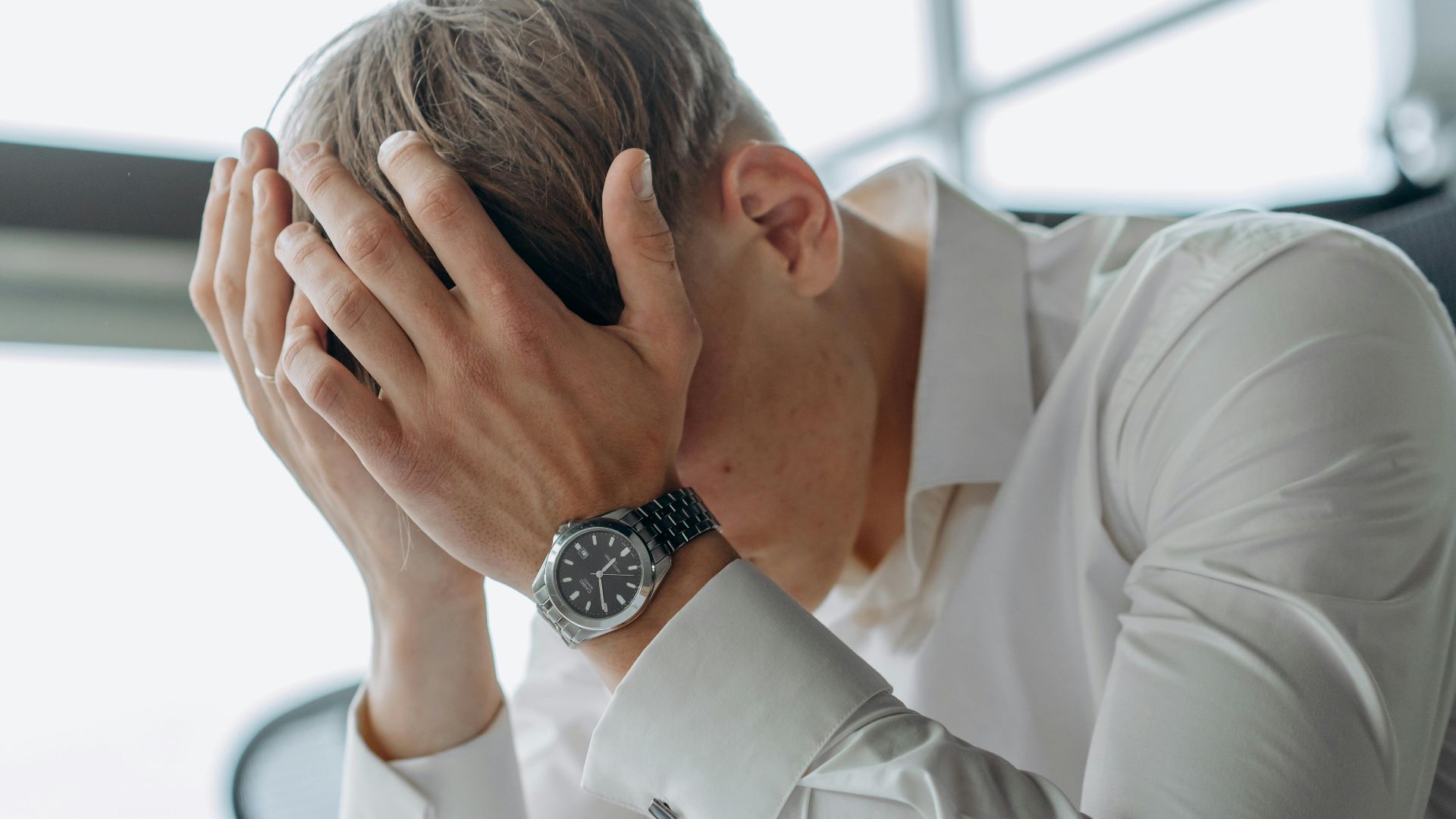 A business professional showing stress and fatigue with head in hands.