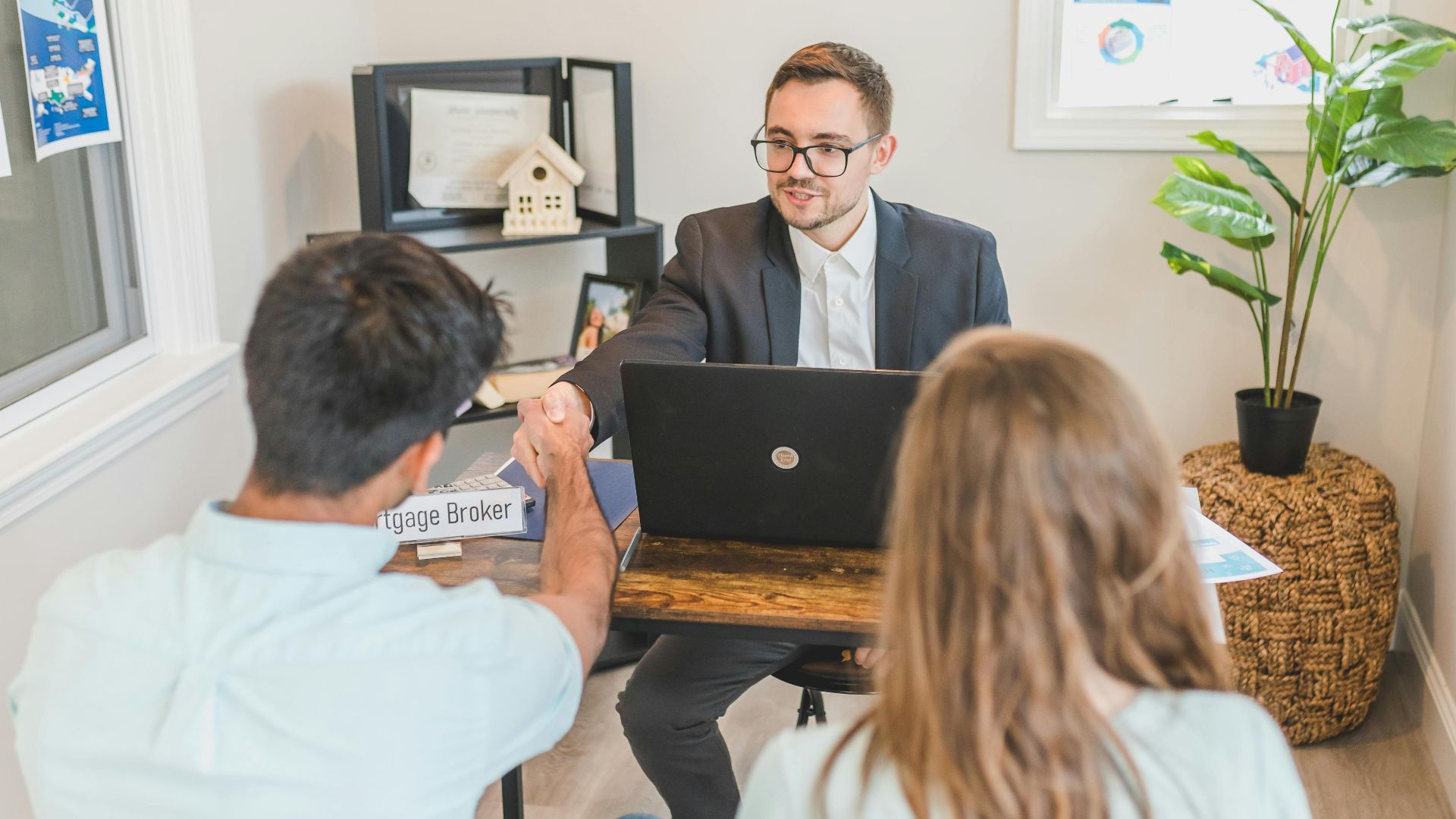 Men and woman discussing mortgage with broker in a modern office setting.