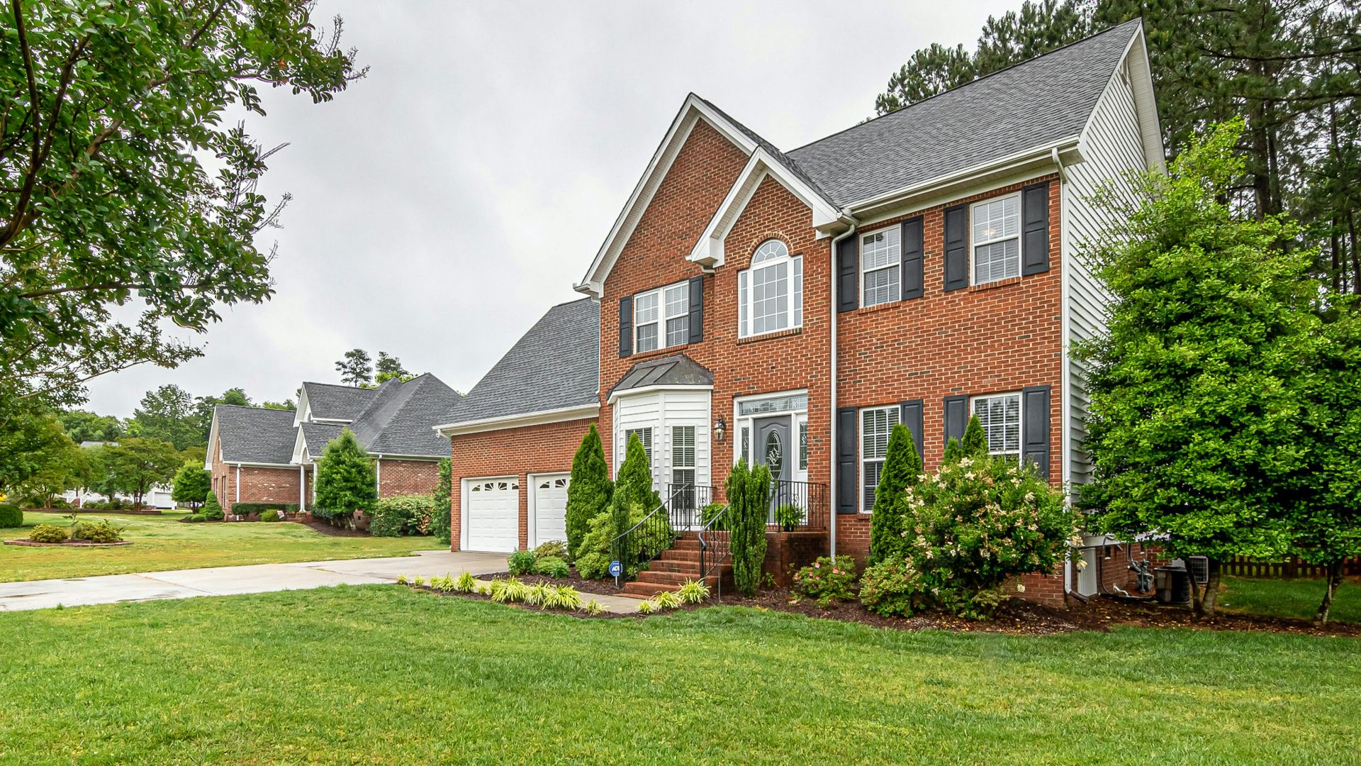 Charming two-story brick house with manicured lawn and trees, perfect family home.