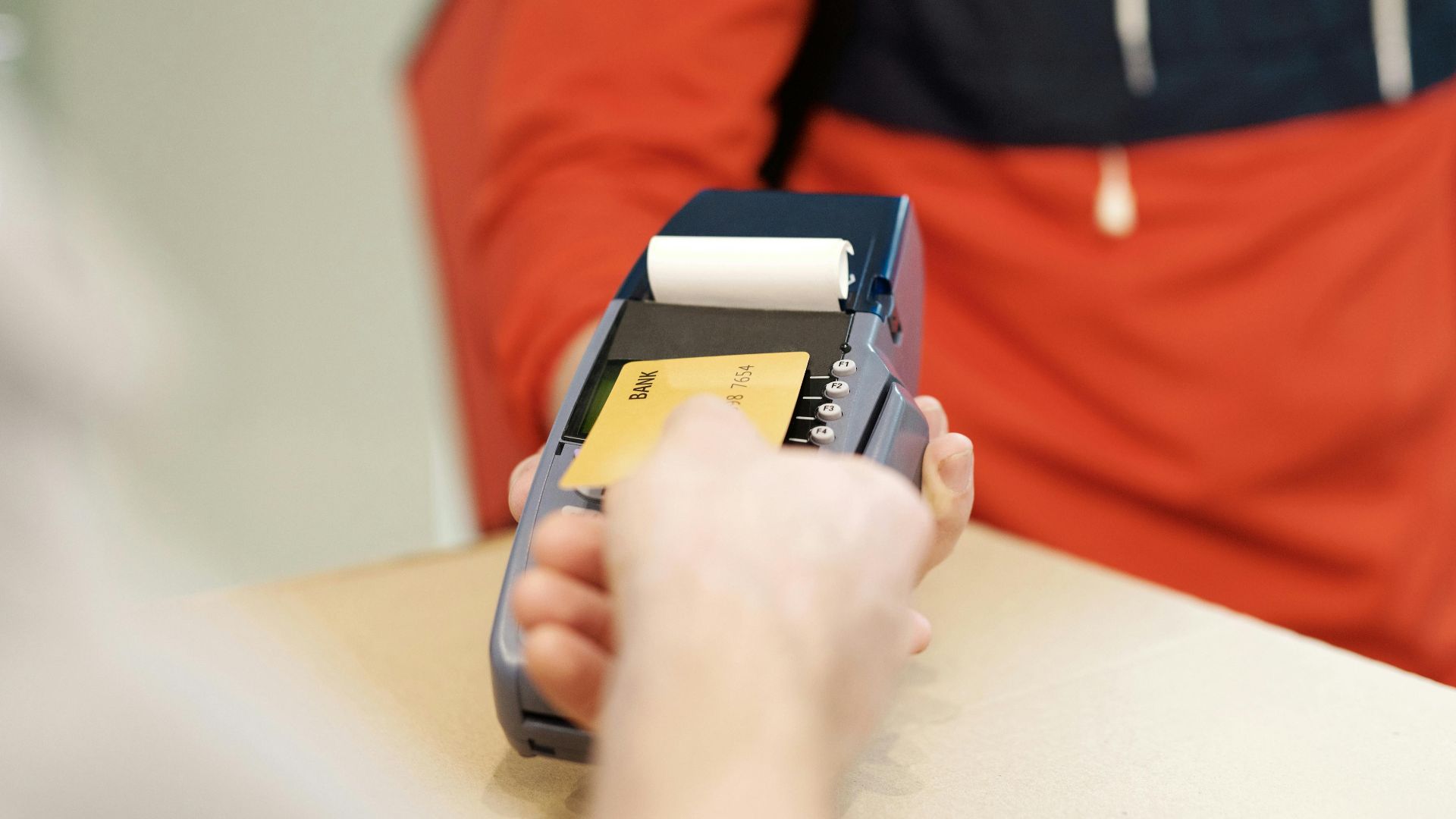 Close-up view of a contactless payment transaction using a credit card on a terminal device.