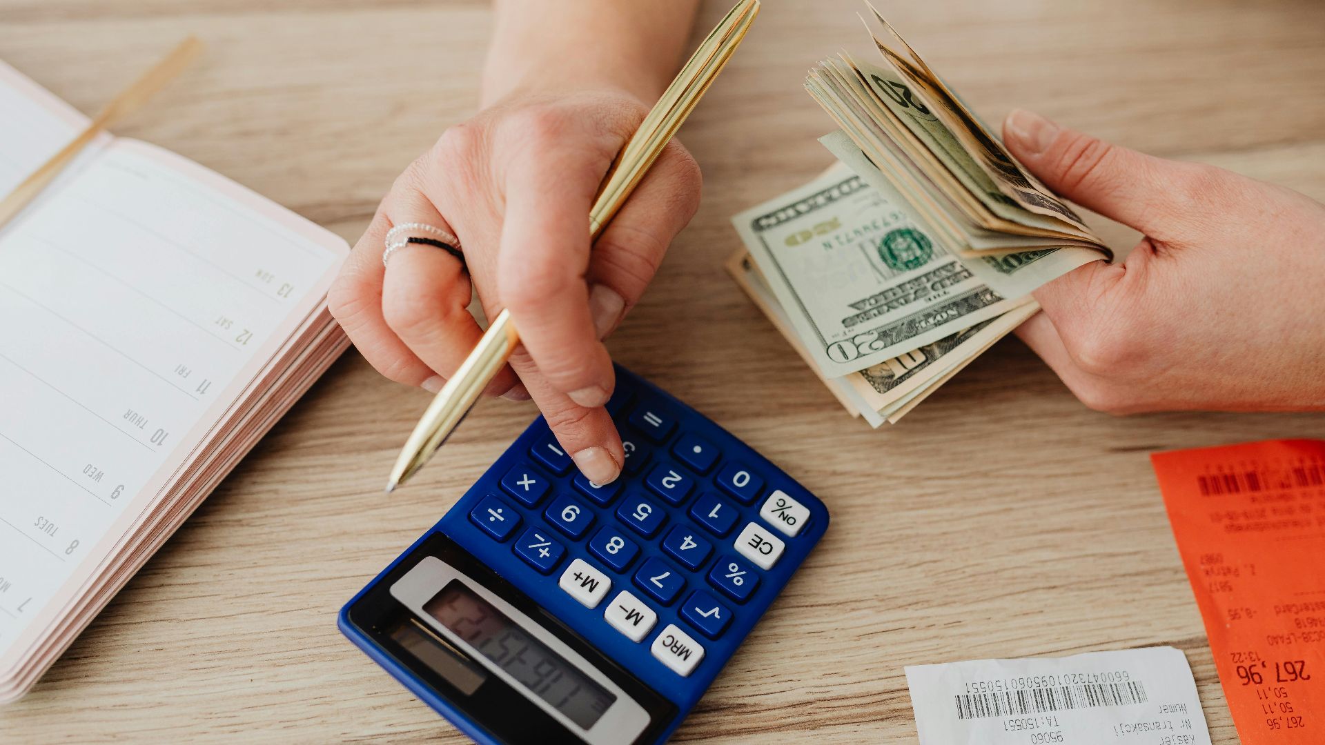 Hands handling cash and calculator for budget planning. Modern financial scene.