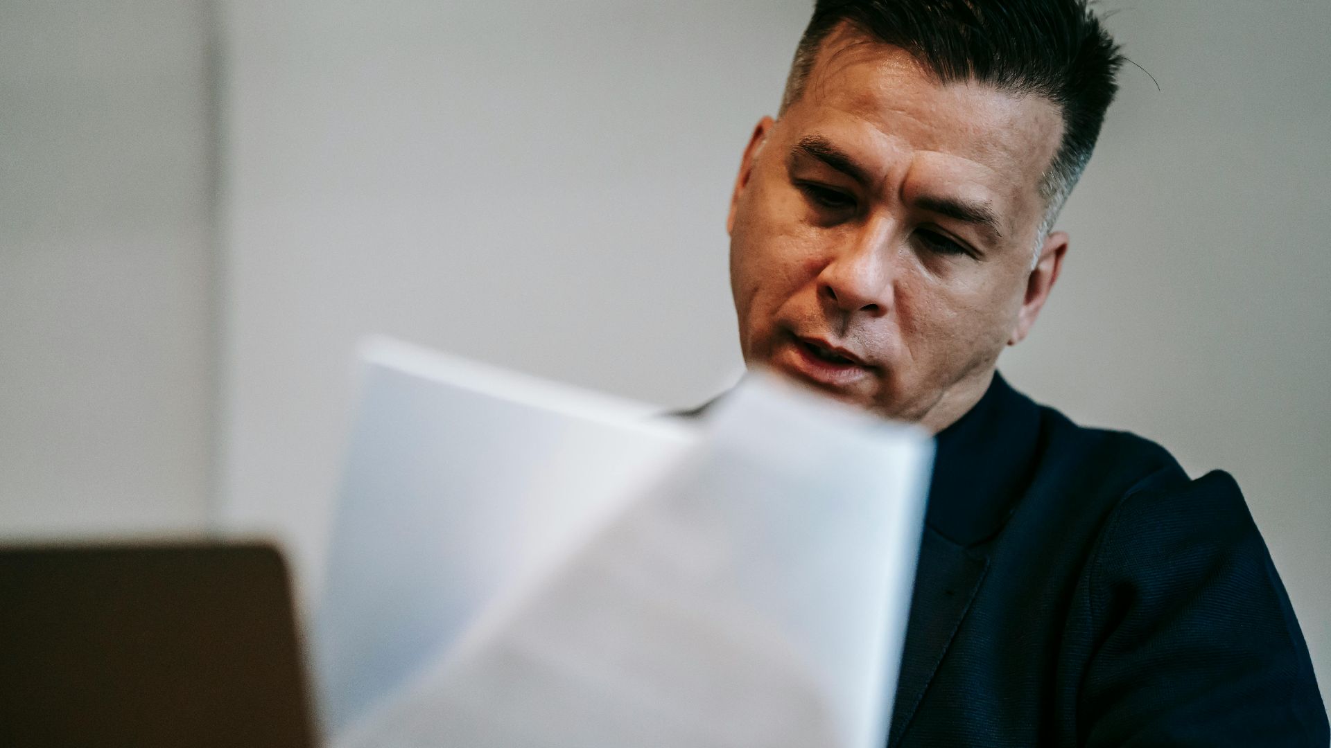 Professional man intently reviewing paperwork at his workstation indoors.