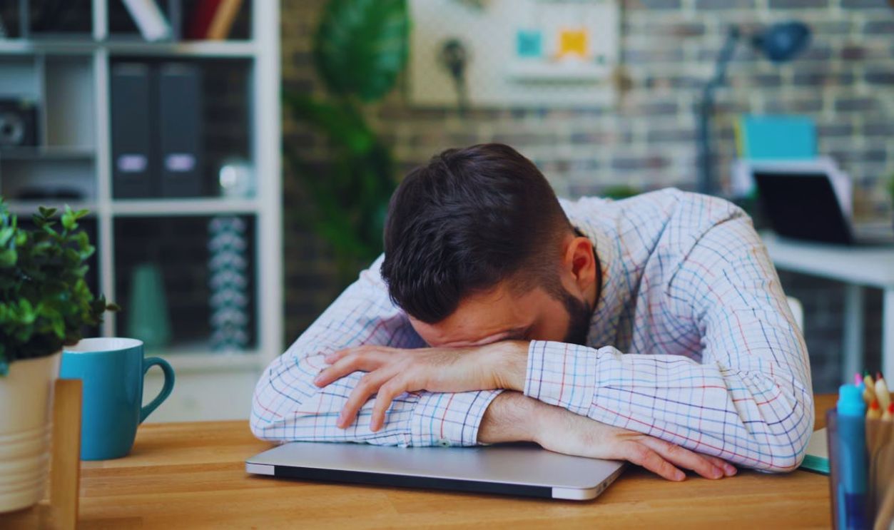 Man in Shirt Lying Down on Table at Office