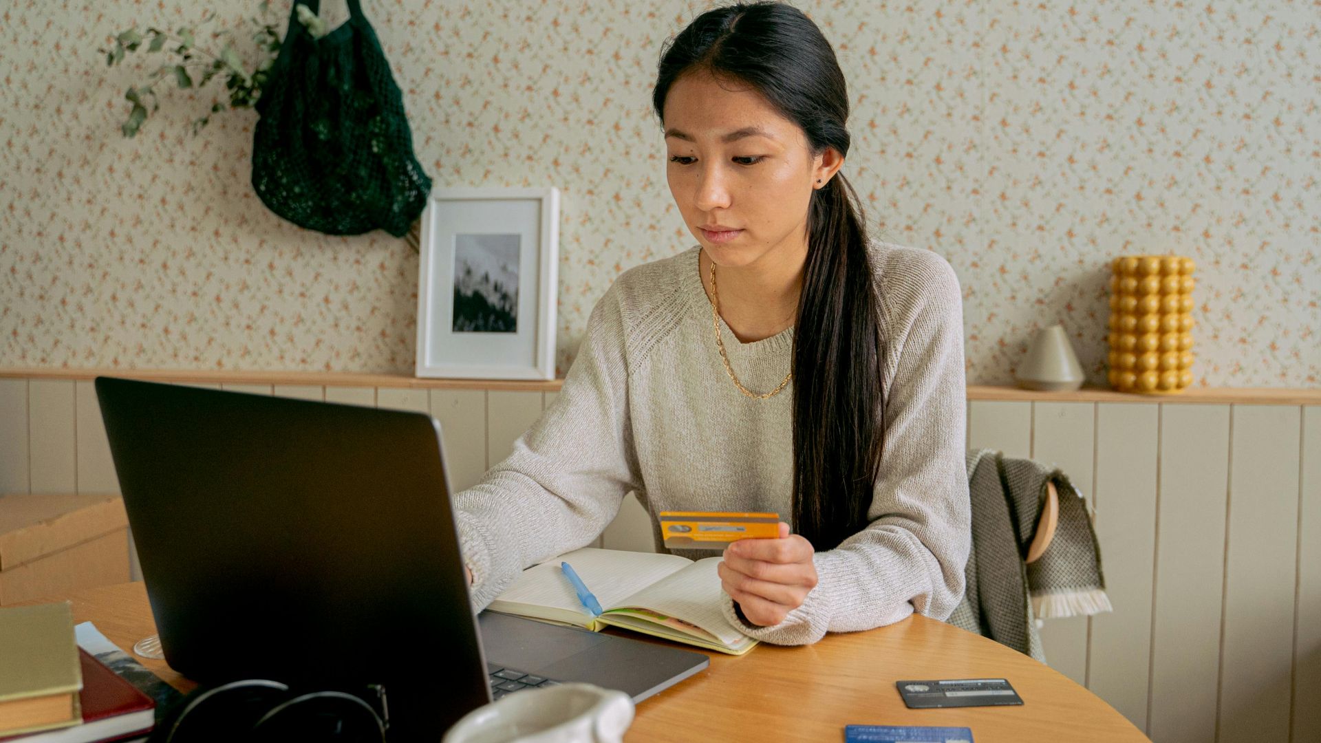 A woman using a laptop and credit card for online shopping at a cozy indoor setting.