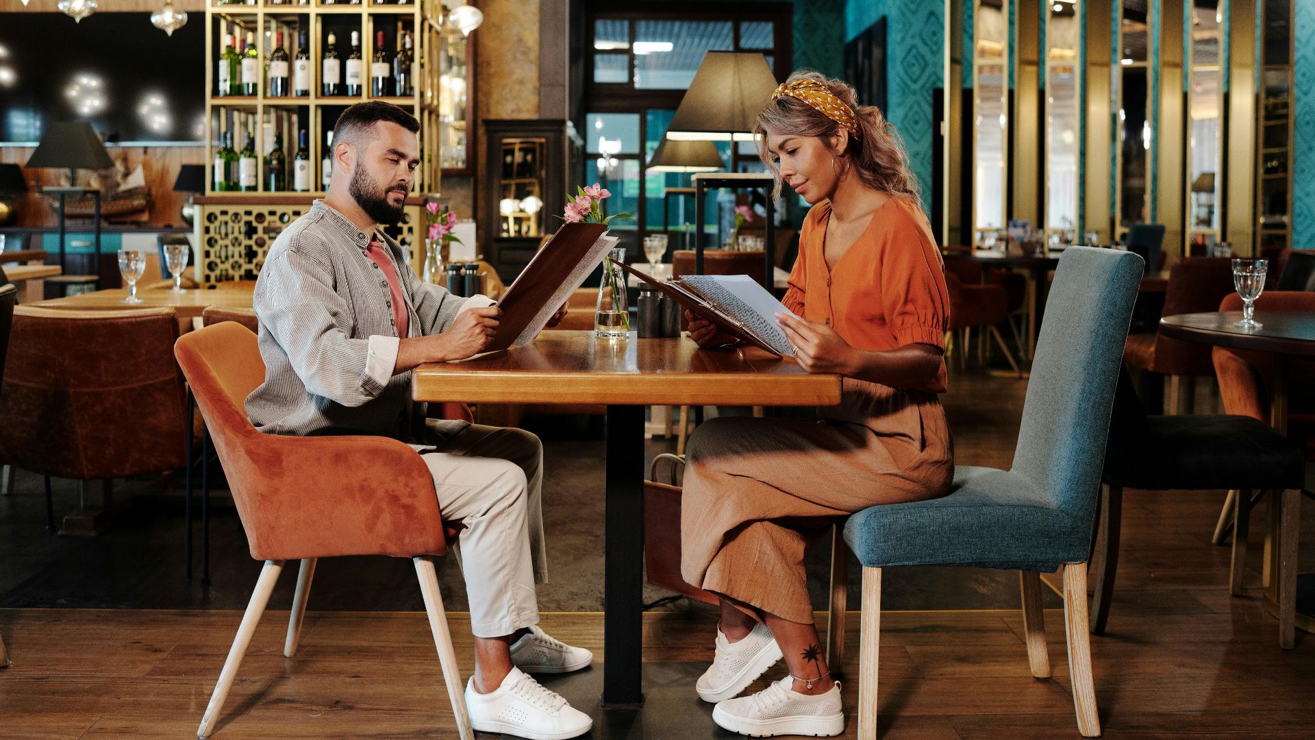 Couple sitting together at a stylish restaurant reviewing the menu, creating a warm and inviting atmosphere.