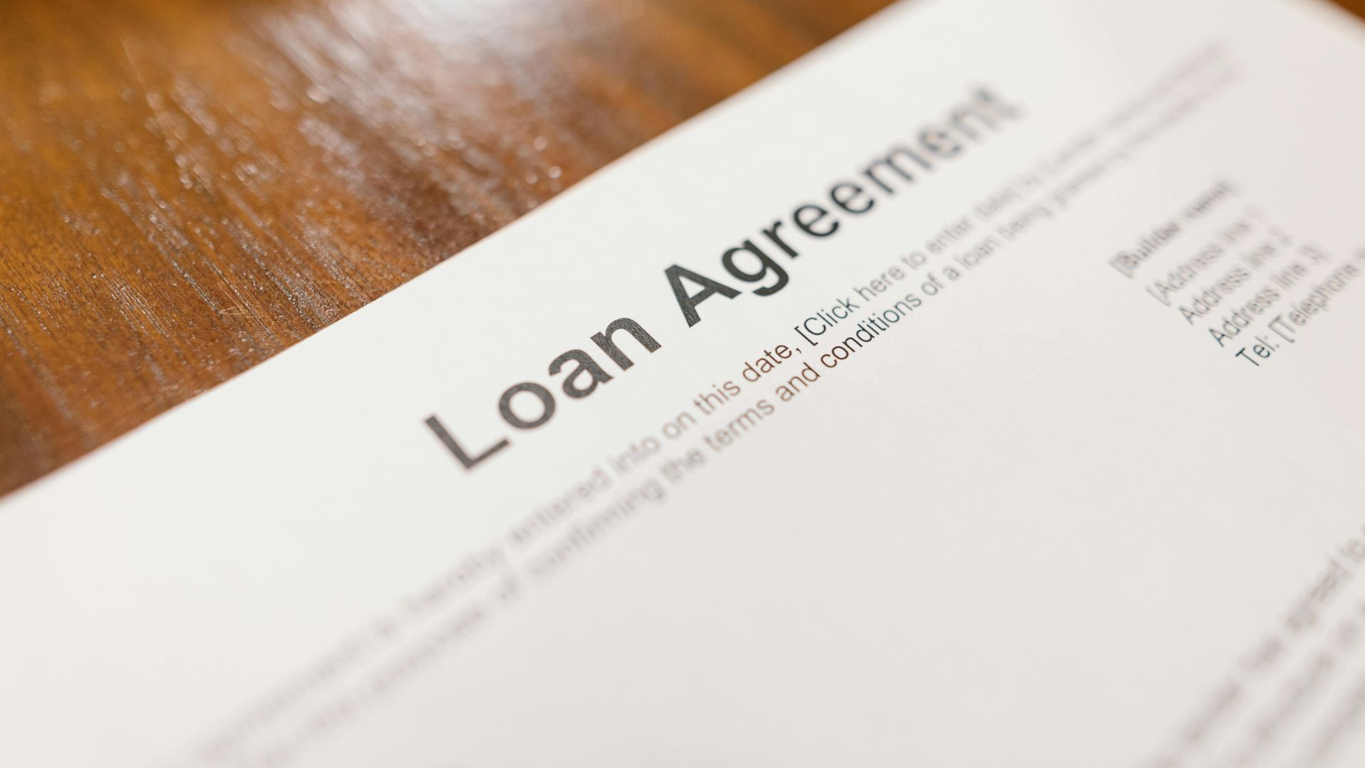 Detailed loan agreement document close-up on a wooden table representing legal and financial concepts.