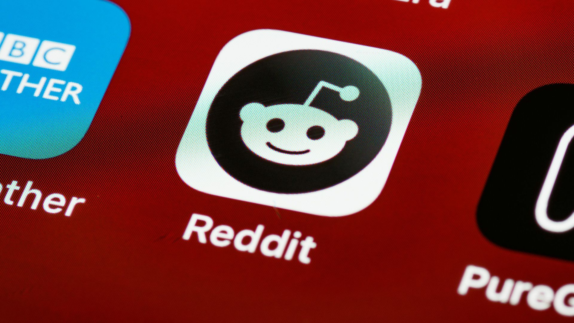 Detailed view of the Reddit app icon on a smartphone screen displaying popular applications.
