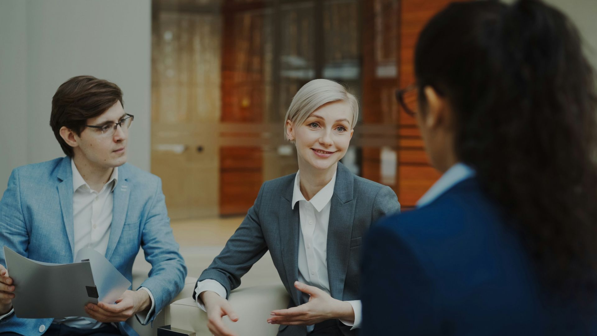 Three people in a business meeting discussing documents