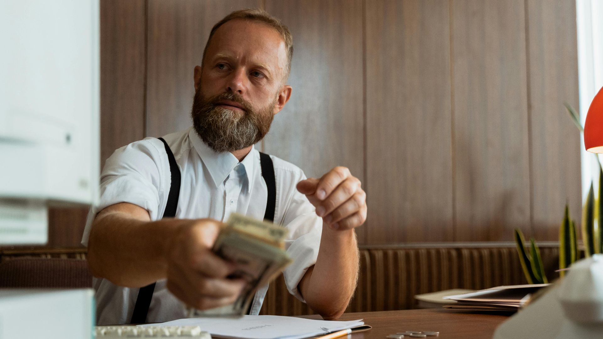 Businessman in a corporate office handling a stack of cash at his desk.