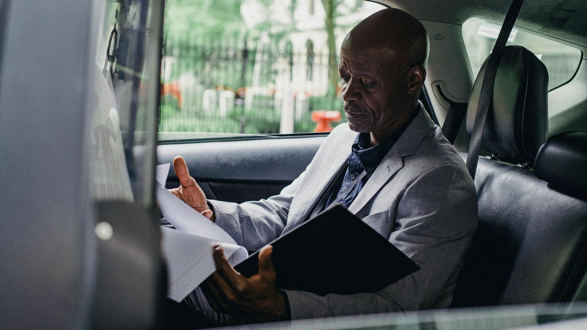 African American businessman reading documents inside a car, demonstrating focus and professionalism.