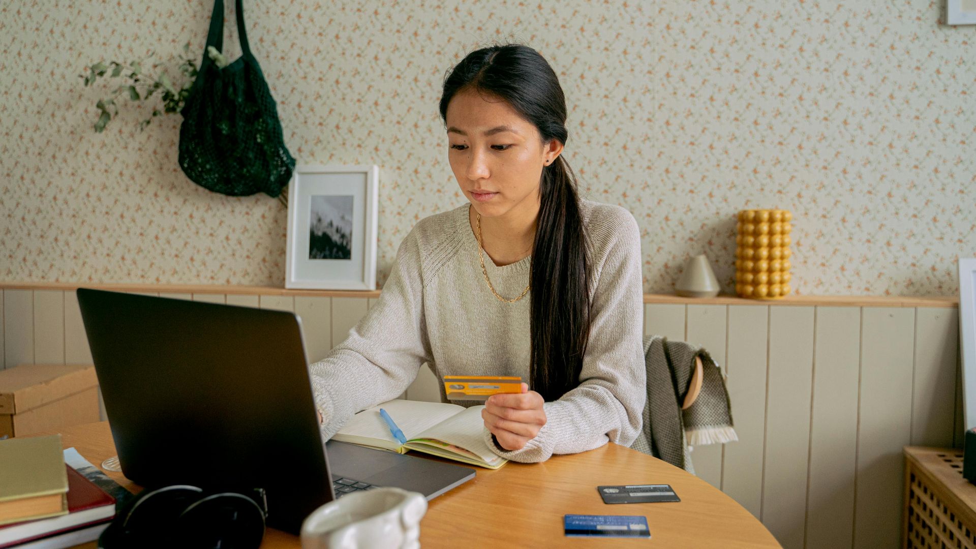 A woman using a laptop and credit card for online shopping at a cozy indoor setting.