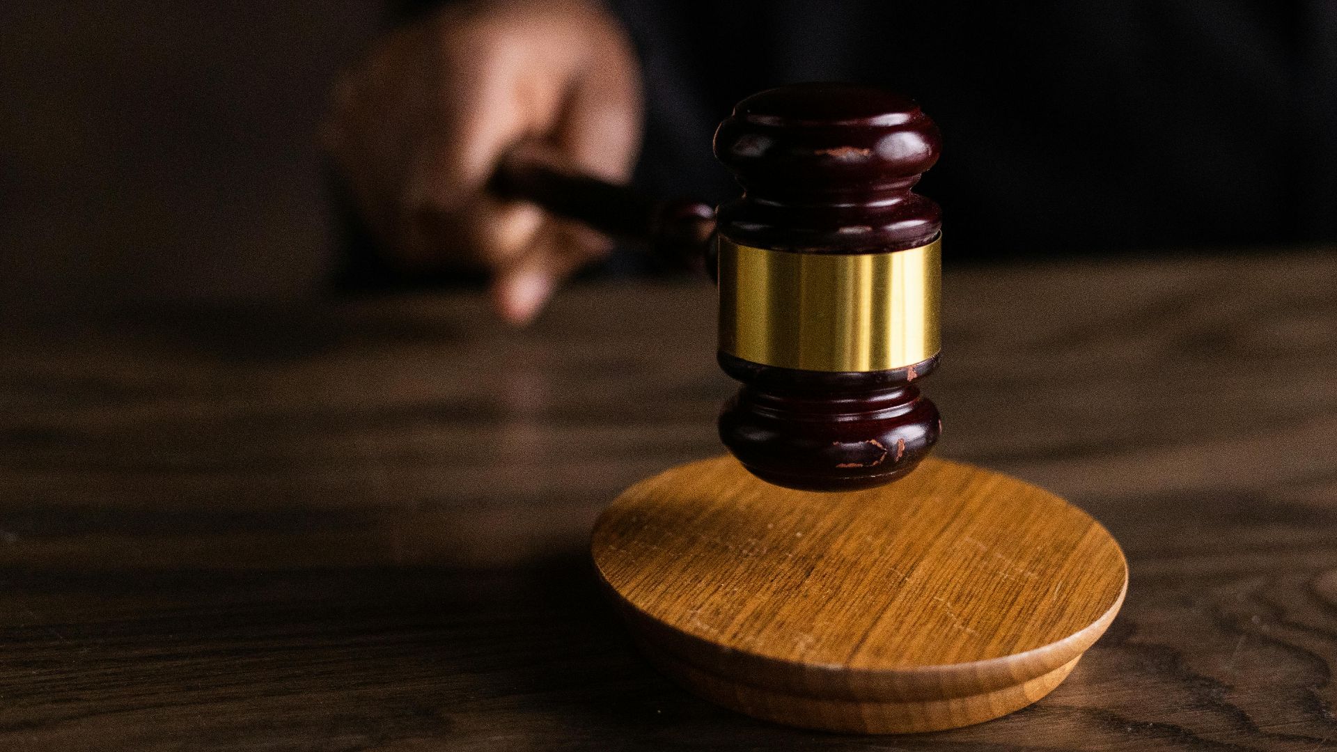 A gavel striking a sound block, symbolizing justice and legal authority in a courtroom setting.