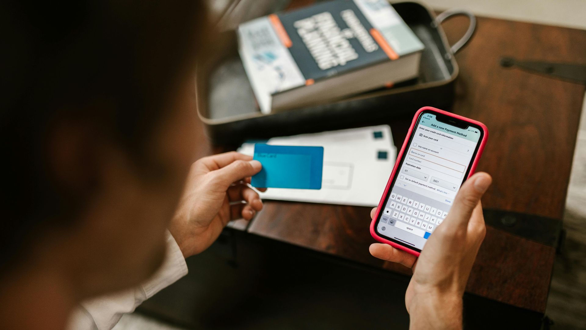Person making an online payment using a smartphone and credit card indoors.