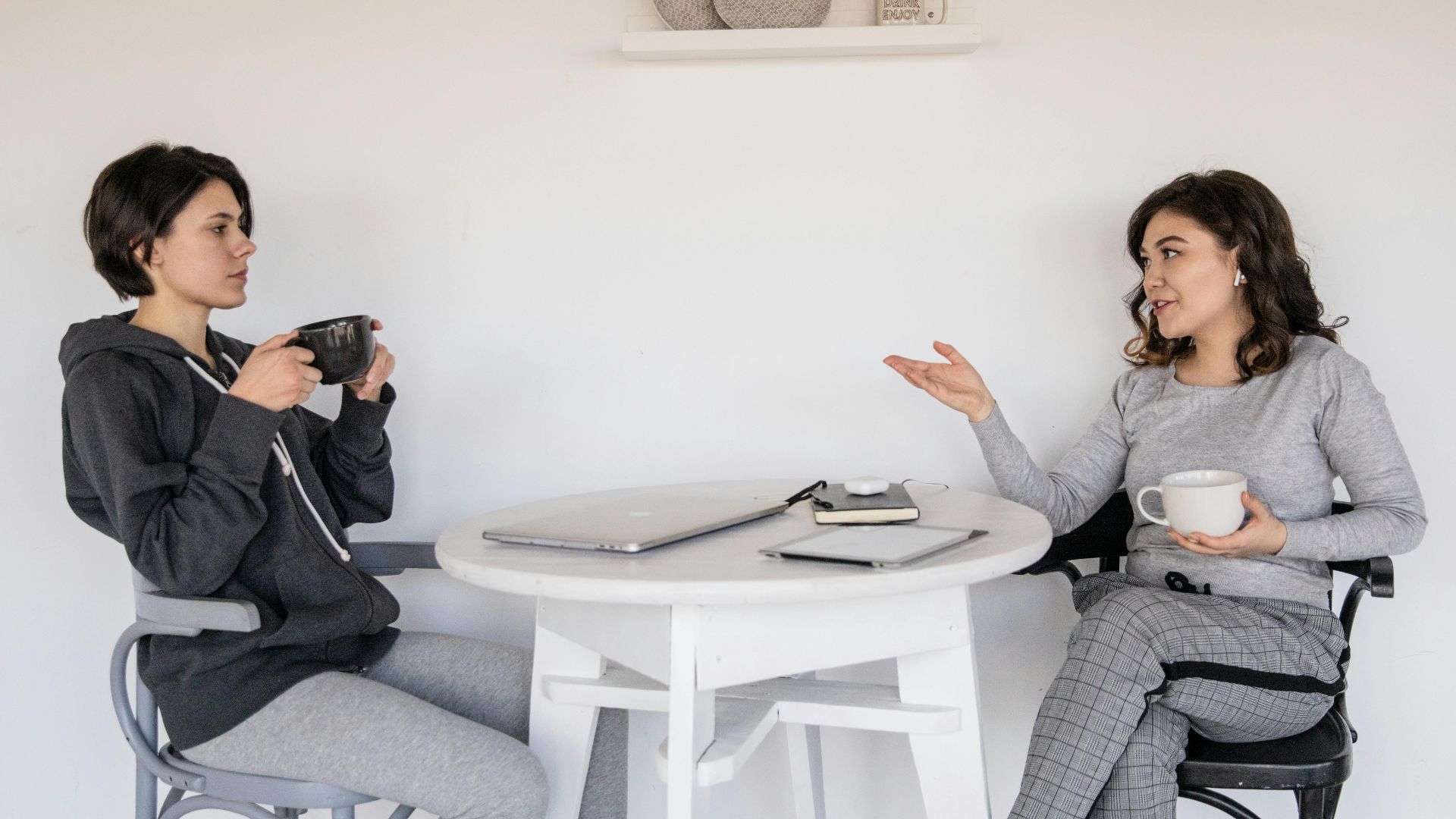 Two women enjoying a casual conversation with coffee in a cozy indoor setting, enhancing connections.