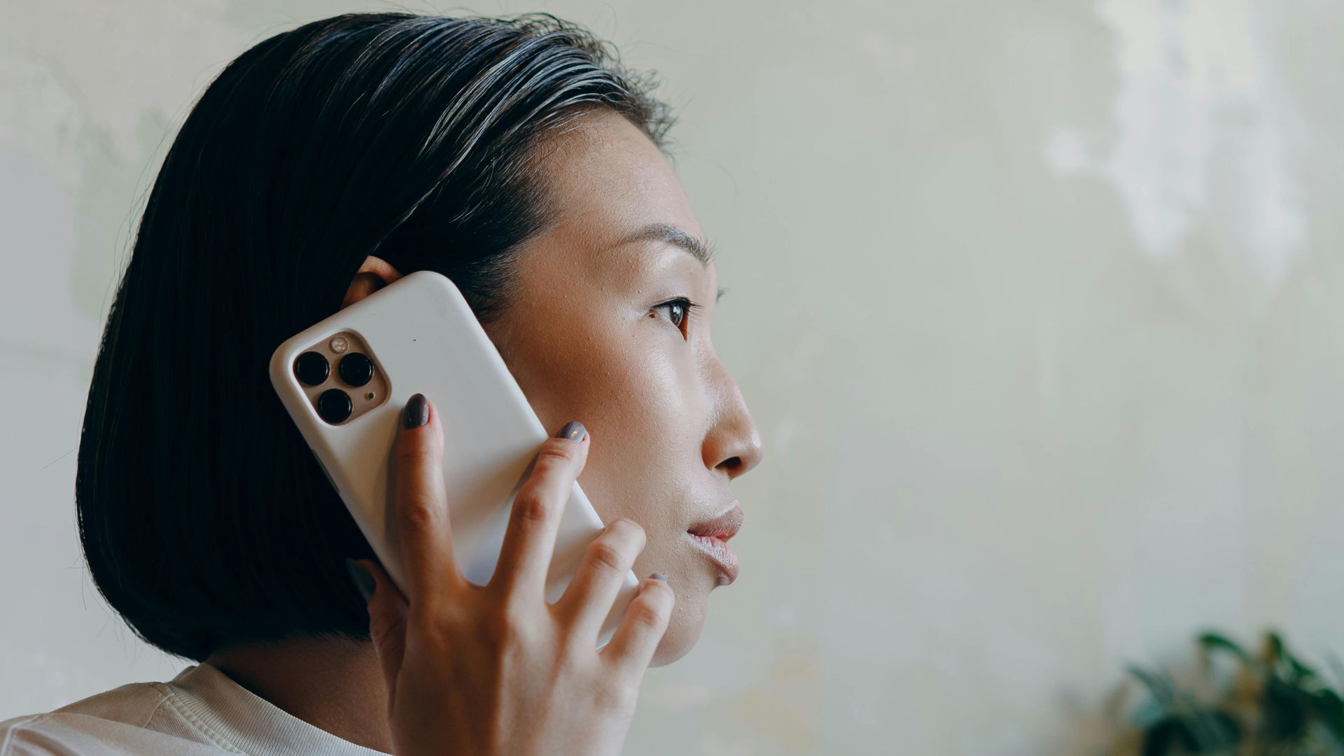 Asian woman in a café making a phone call while enjoying coffee.