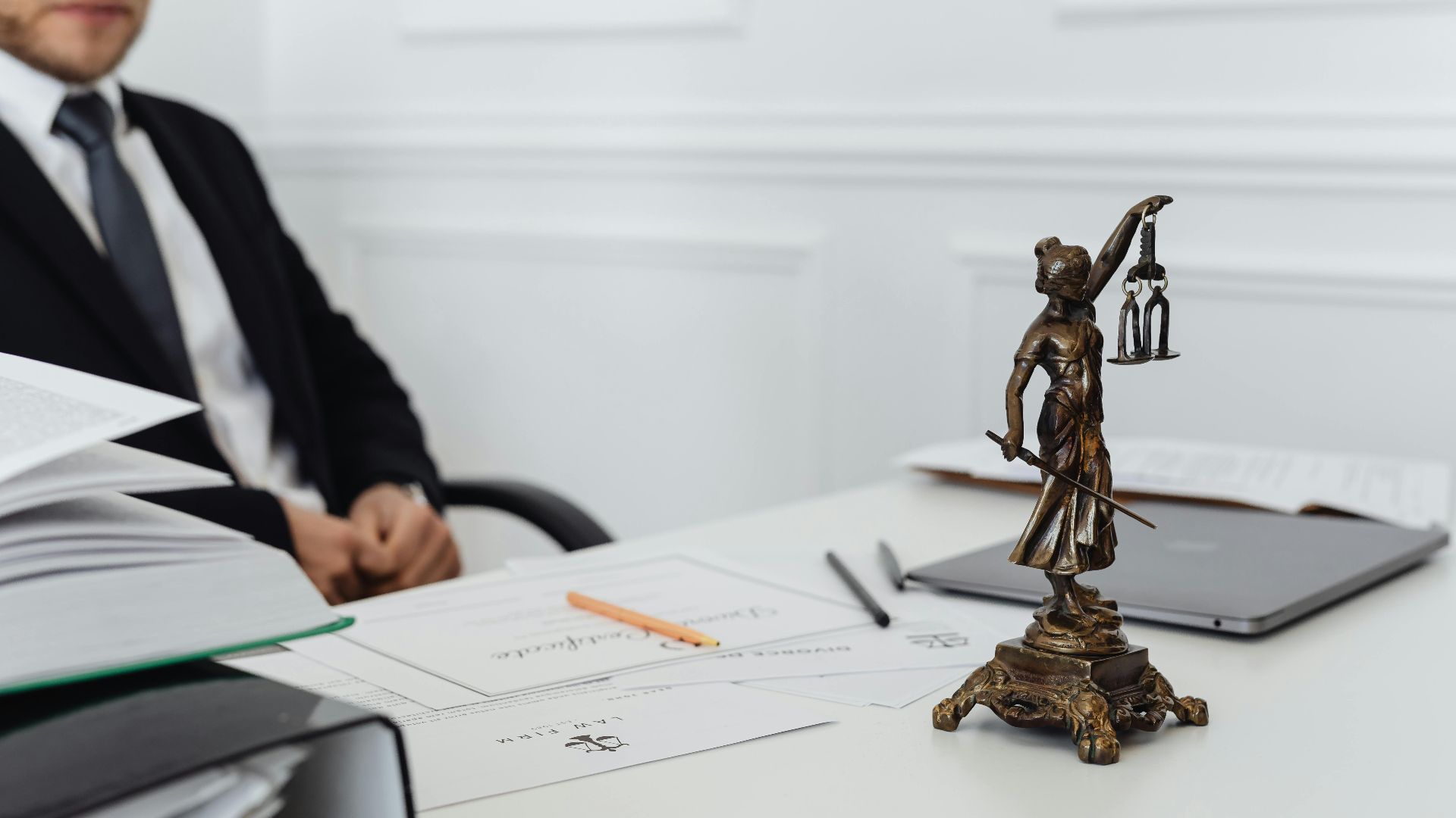 A legal professional's workspace featuring Lady Justice statue, documents, and a laptop.