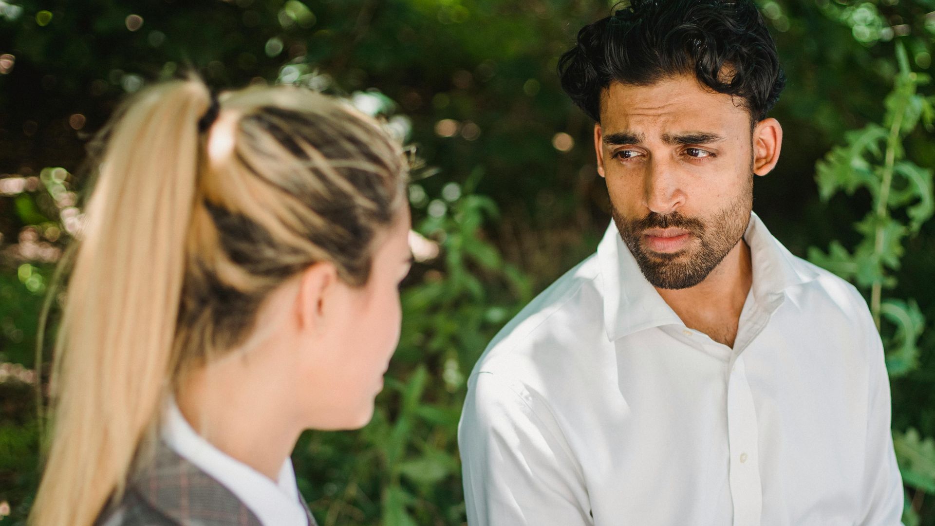 Two colleagues having a meeting outdoors over coffee, engaged in discussion.