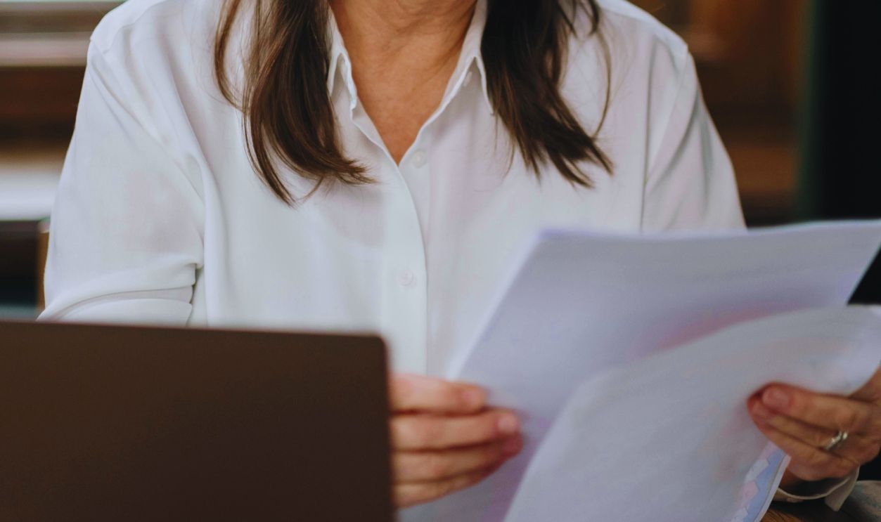 An Elderly Woman Wearing Black Framed Eyeglasses while Reading Documents
