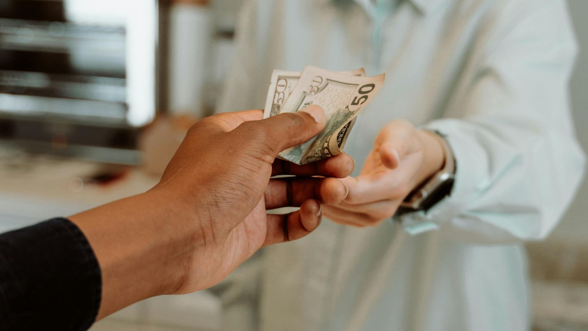 A female cashier receiving cash payment from a customer at a retail store.